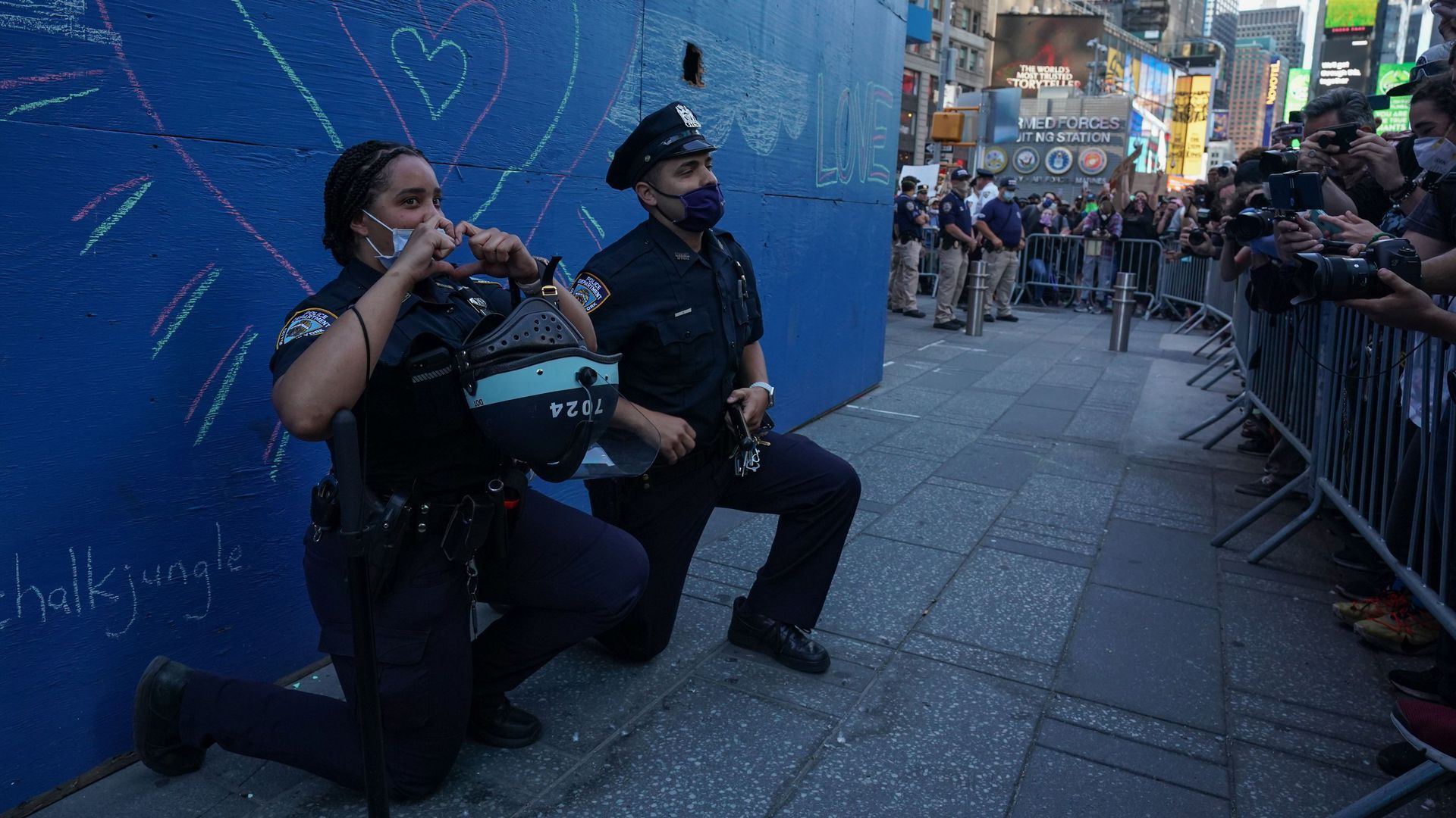 Two New York City police officers take a knee during a demonstration in Times Square over the death of George Floyd by a Minneapolis police officer at a rally on Sunday in New York. 
