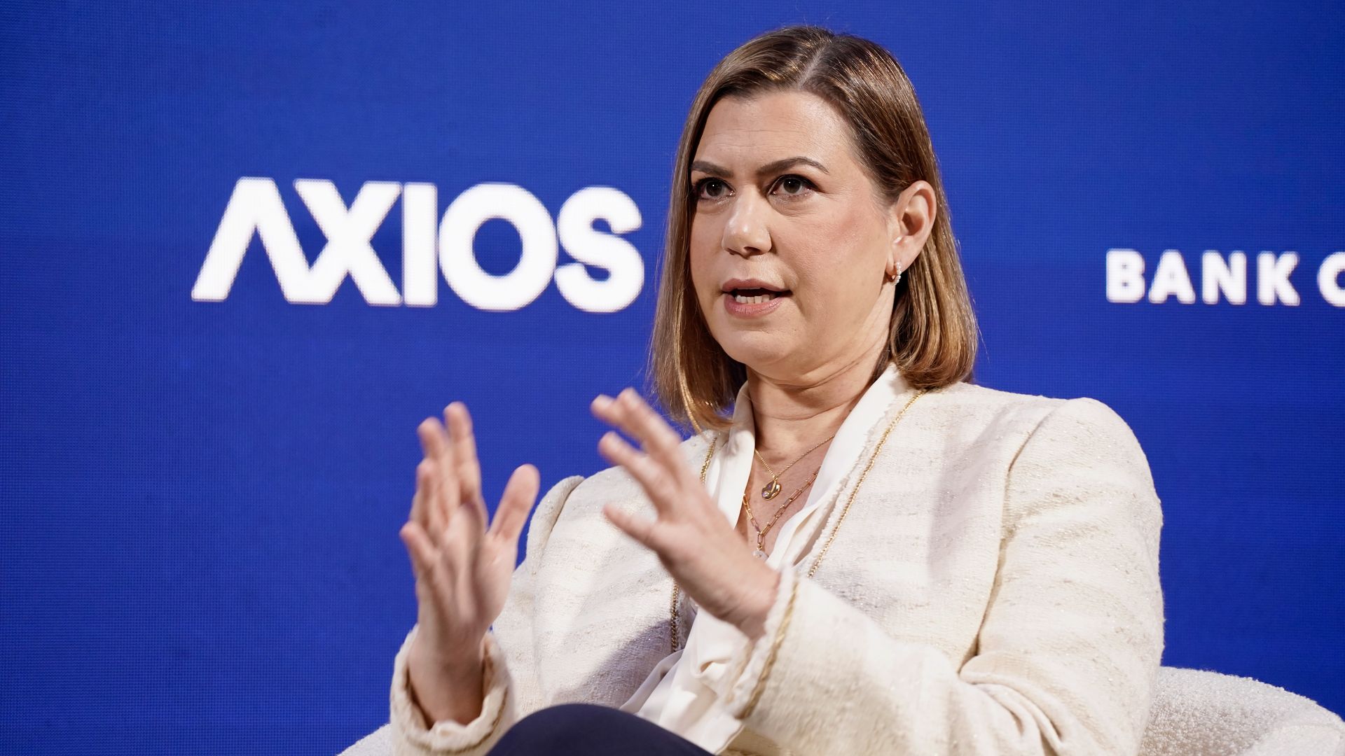 Sen. Elissa Slotkin gestures as she speaks against a blue backdrop during an Axios event wearing a cream blazer.