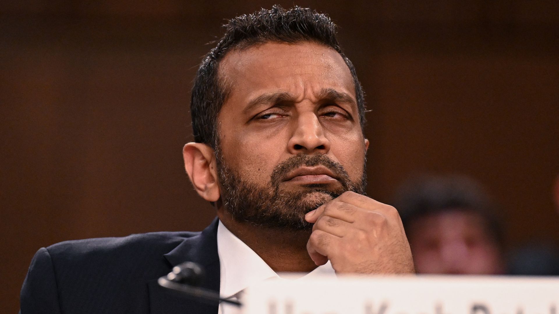 FBI director Kash Patel sits in front of a microphone while testifying before Congress