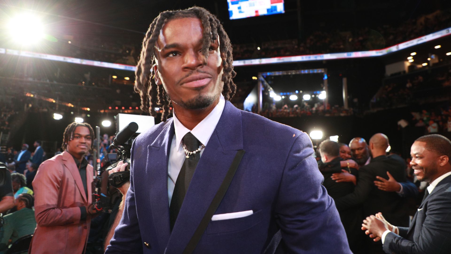 A man in a suit smiles while looking ahead. 