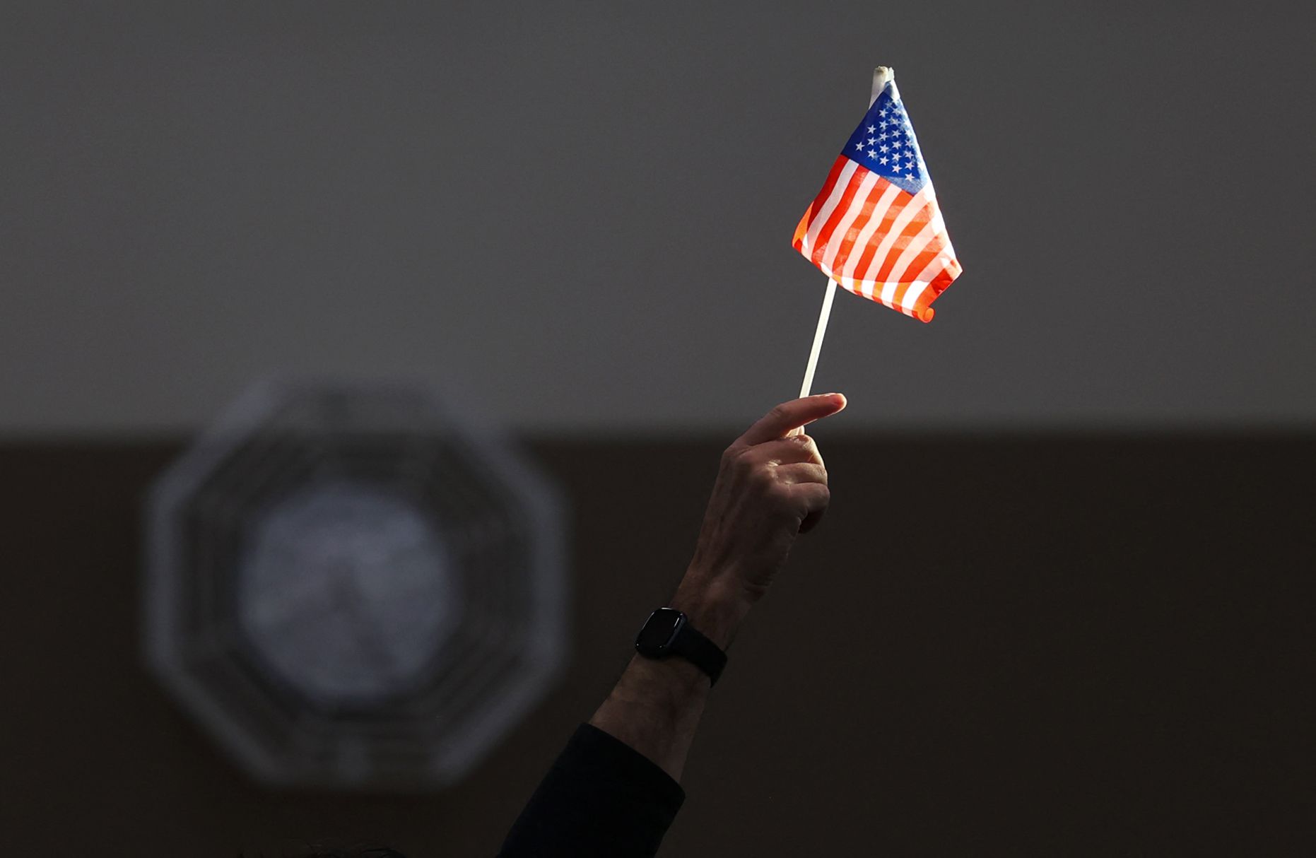 A person holds an American flag up into the light. 