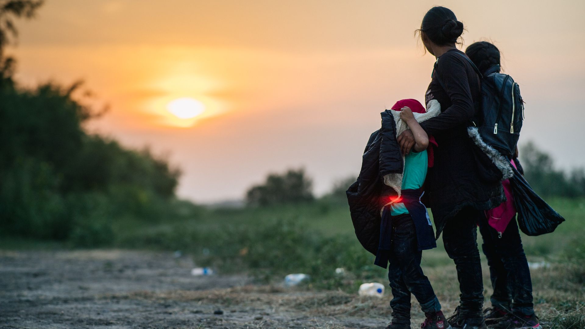A migrant family is seen looking at the setting sun while awaiting processing after crossing the U.S.-Mexico border.