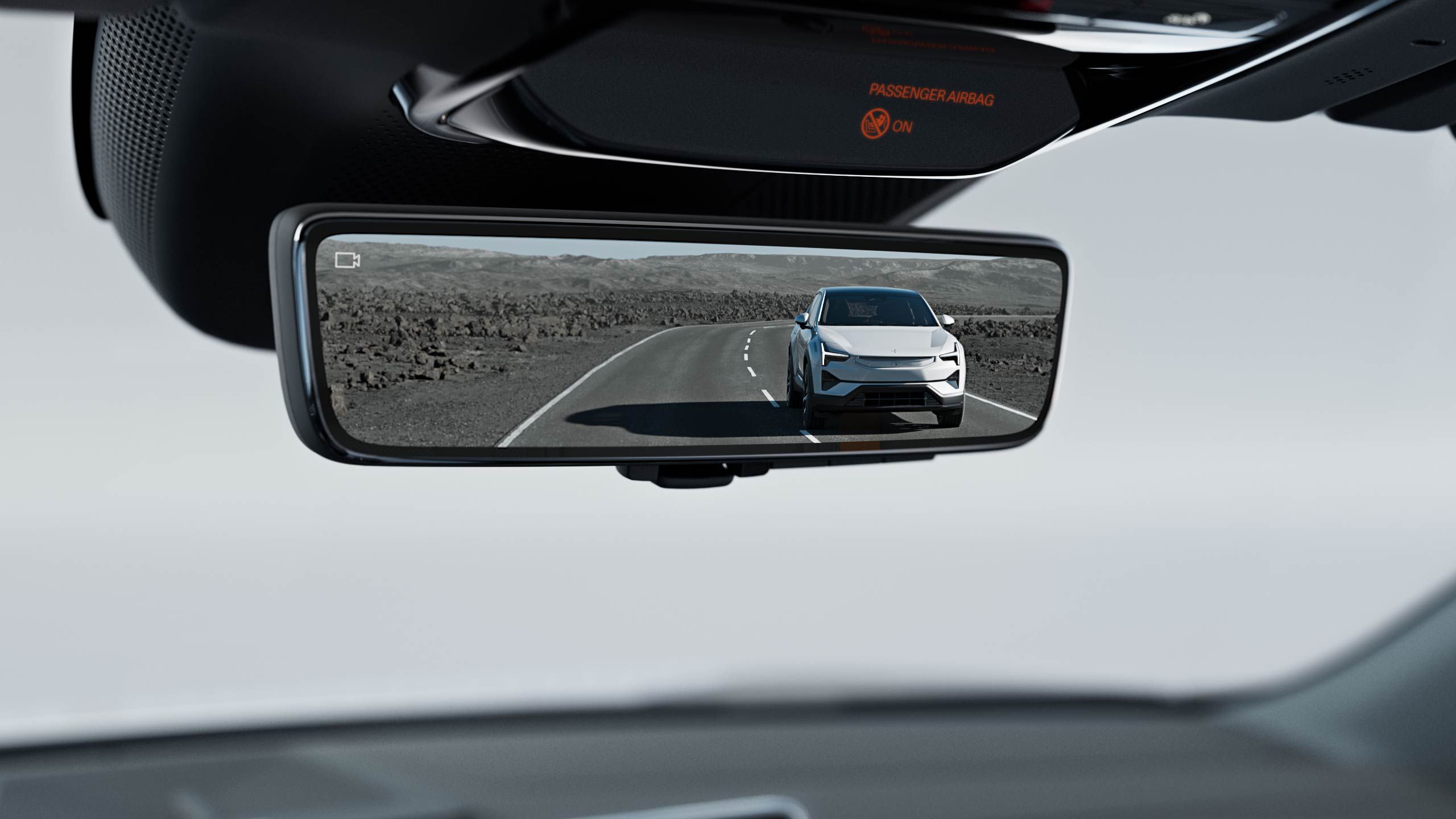 Rearview camera display instead of a mirror shows a white SUV on a straight desert highway, with rocky terrain and distant mountains; 