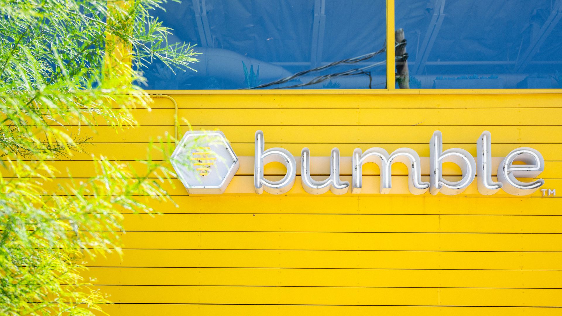 The logo of the dating company bumble on a yellow exterior wall of a building