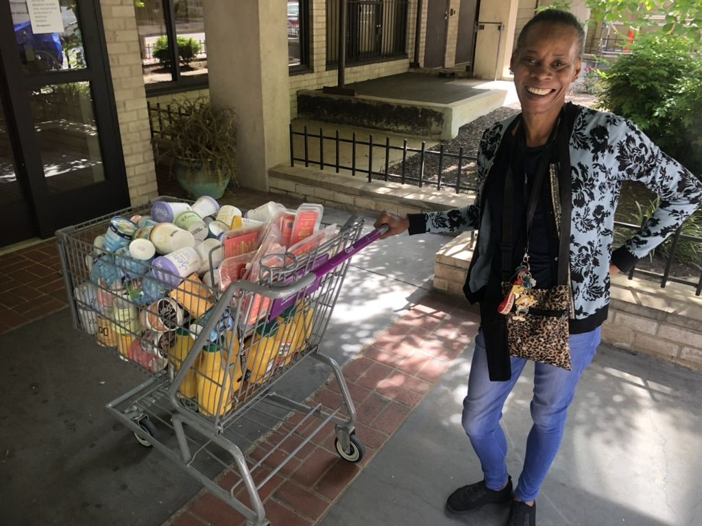 A woman smiles by a shopping cart filled with ice cream