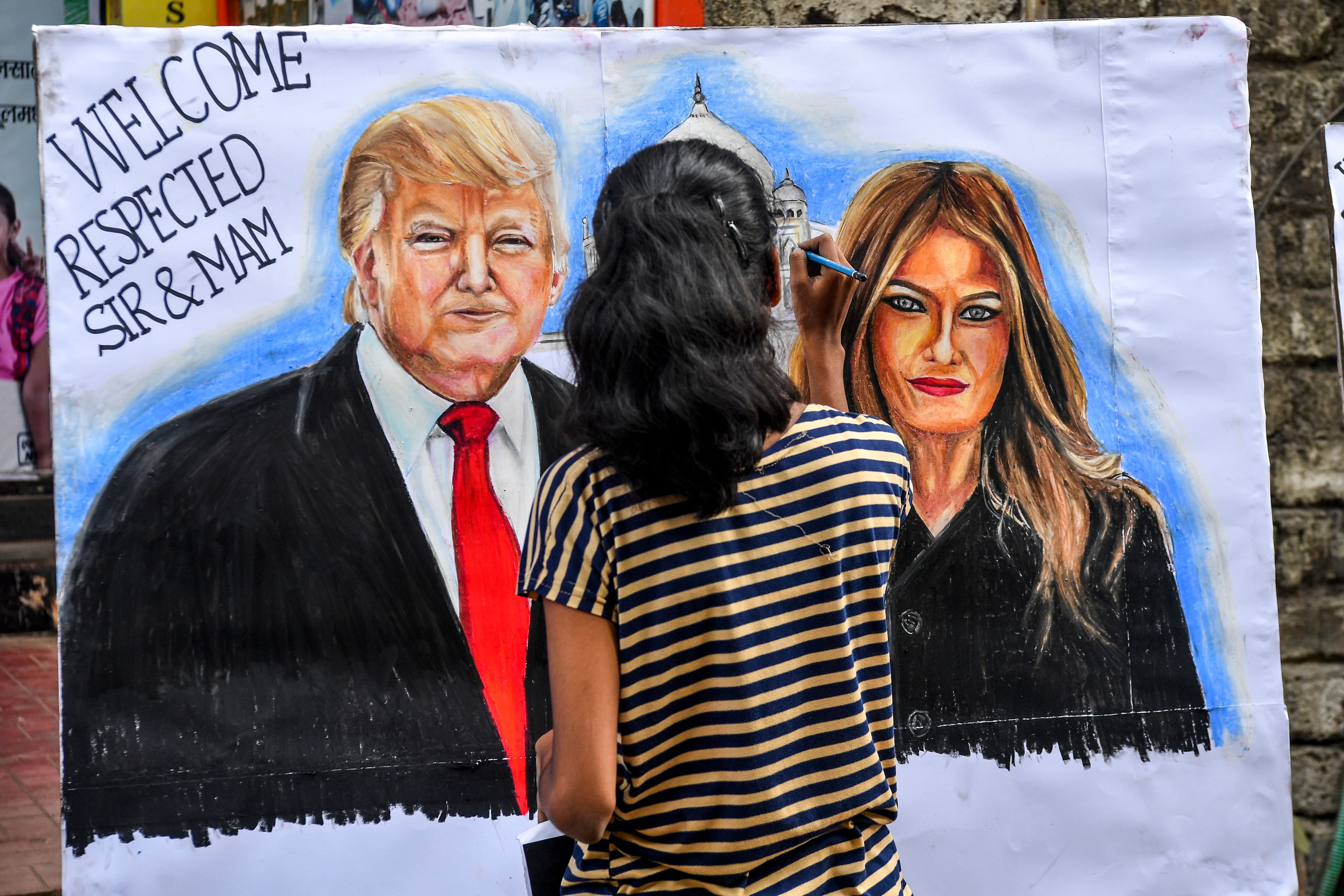 A student paints on a canva faces of US President Donald Trump (L) and his wife Melania, in the street in Mumbai on February 21