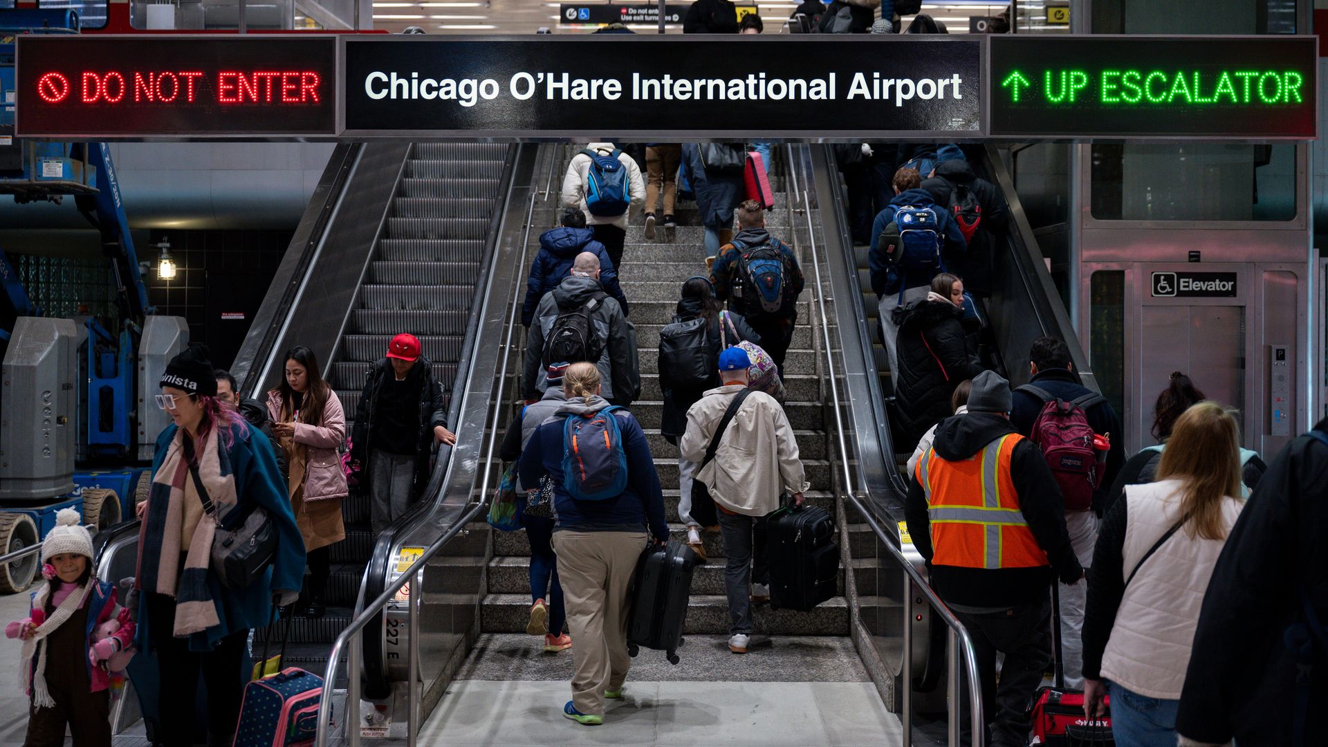 Photo of travelers going up flights of stairs at an airport. 