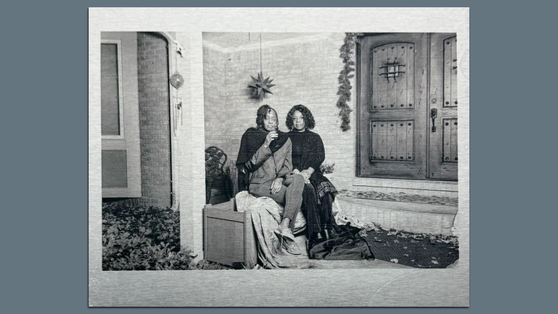 A portrait of two people sitting near an old wooden door. black and white. 