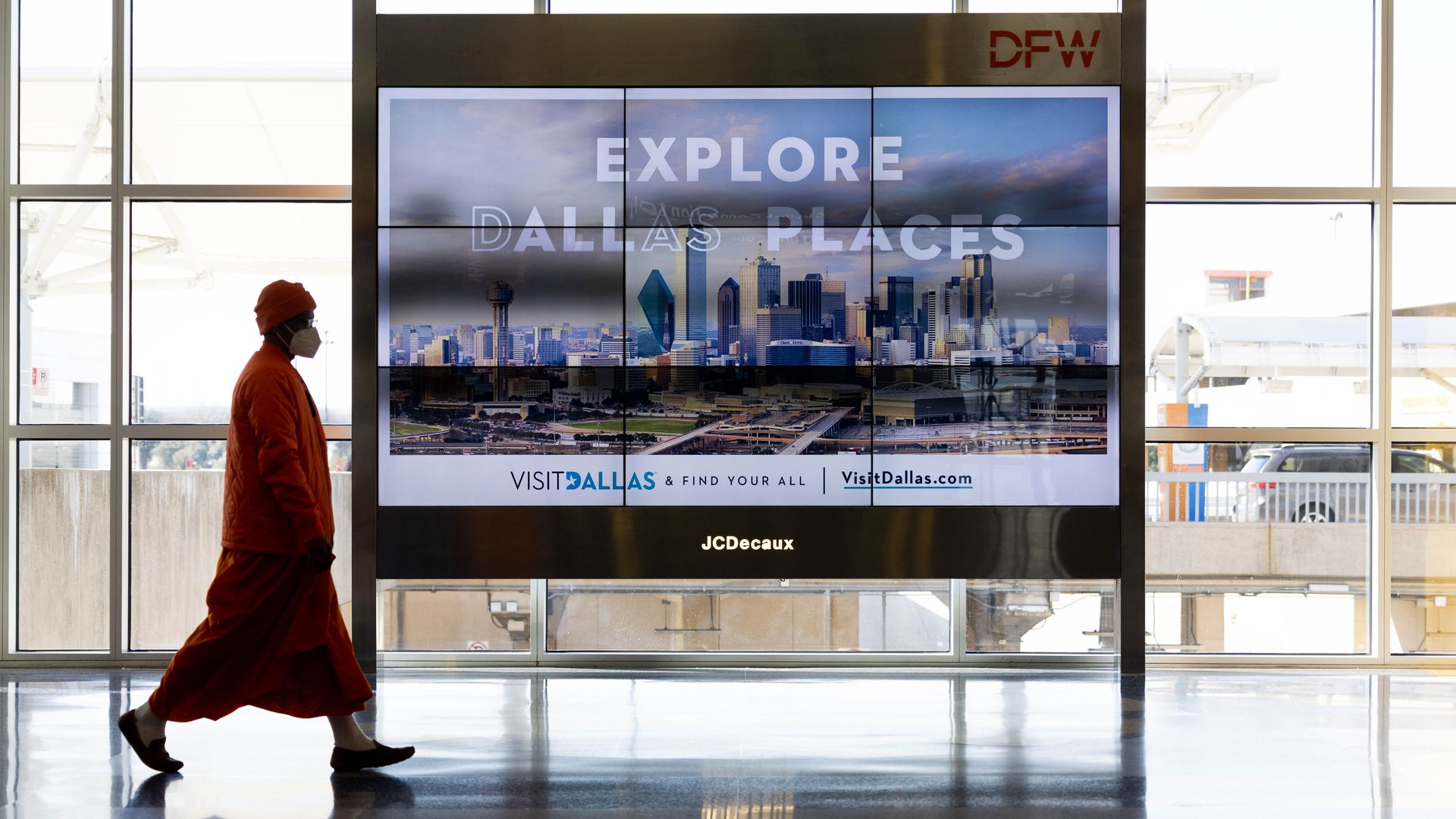 A woman walks in an airport wearing a mask