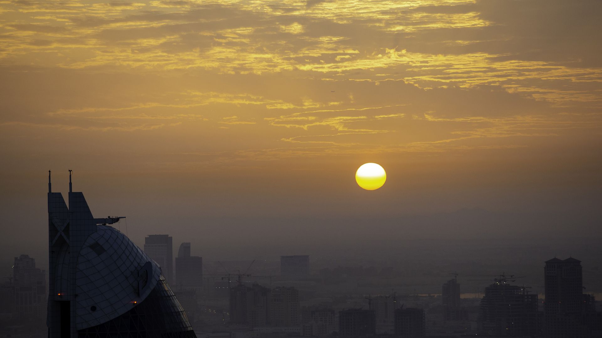 Dubai skyscraper and sun in background.