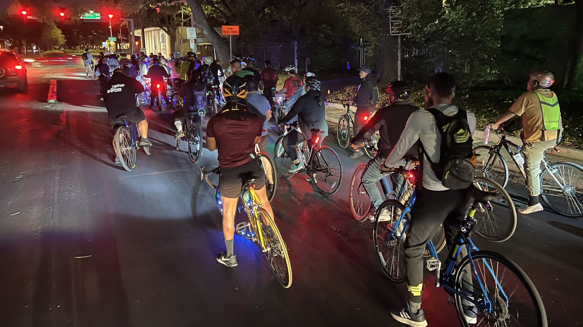 A group of about 100 cyclists stopped at a red light at night