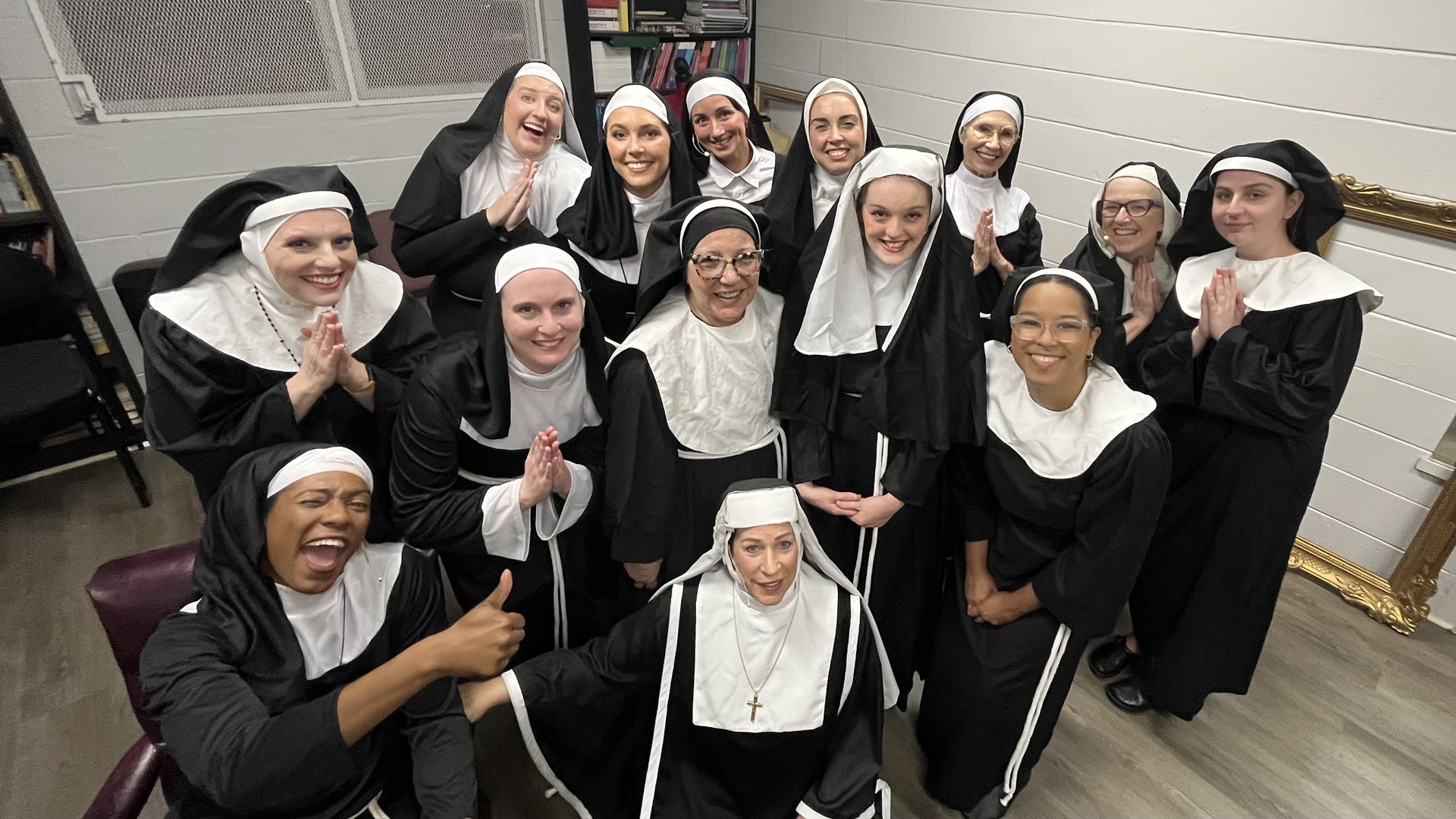 A group of women dressed as nuns pose and smile at a camera.