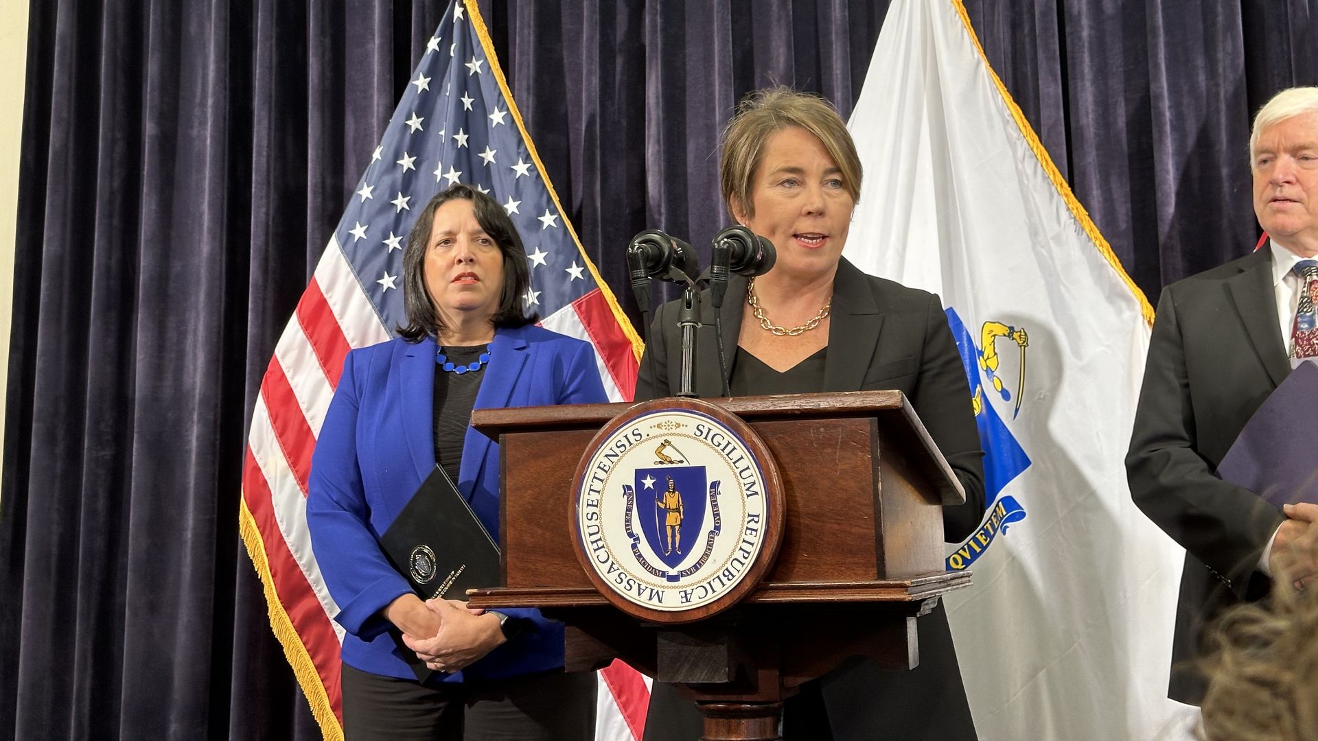 Gov. Maura Healey speaks at a podium inside the Massachusetts State House during a news conference. 