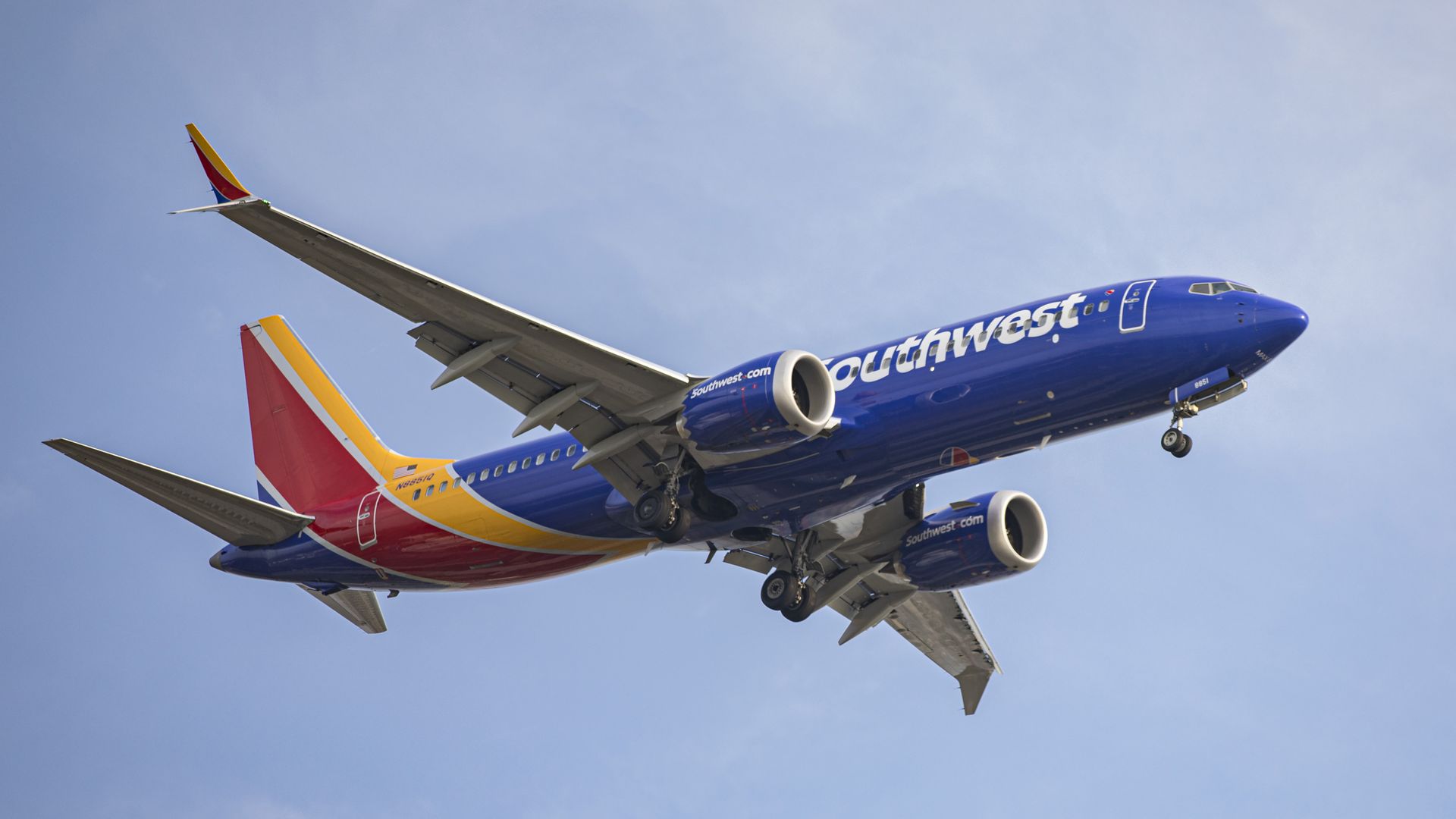 An airplane covered with a Southwest logo and signature blue, yellow and red colors is descending.