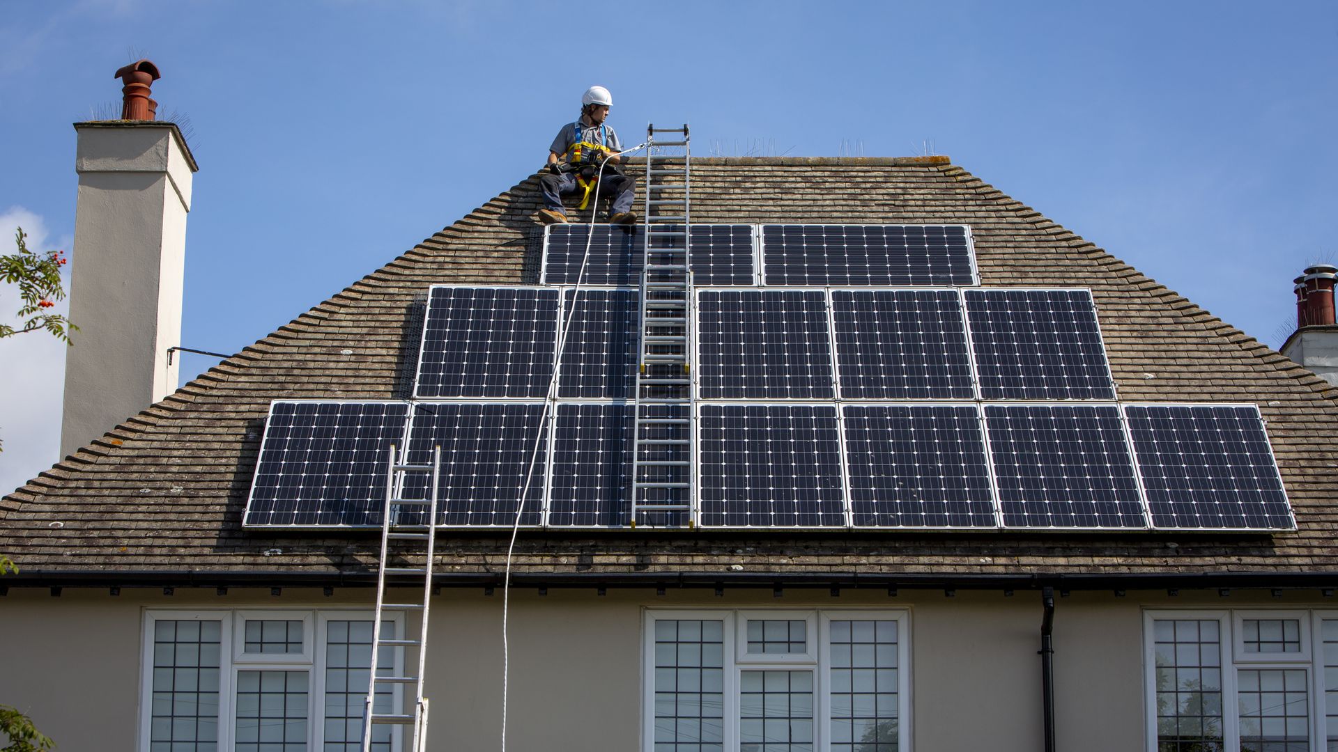 A man on a roof installing a solar panel.