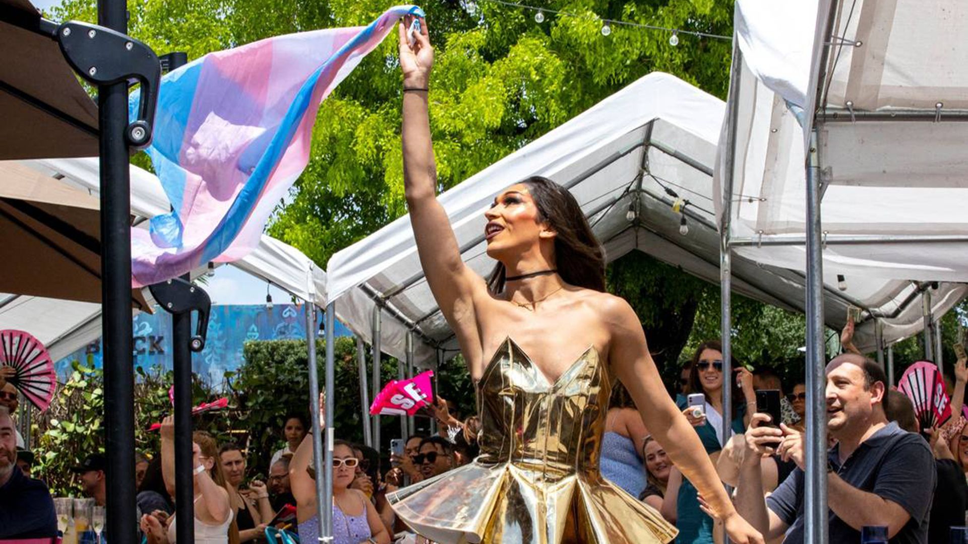 drag queen waves trans flag mid performance