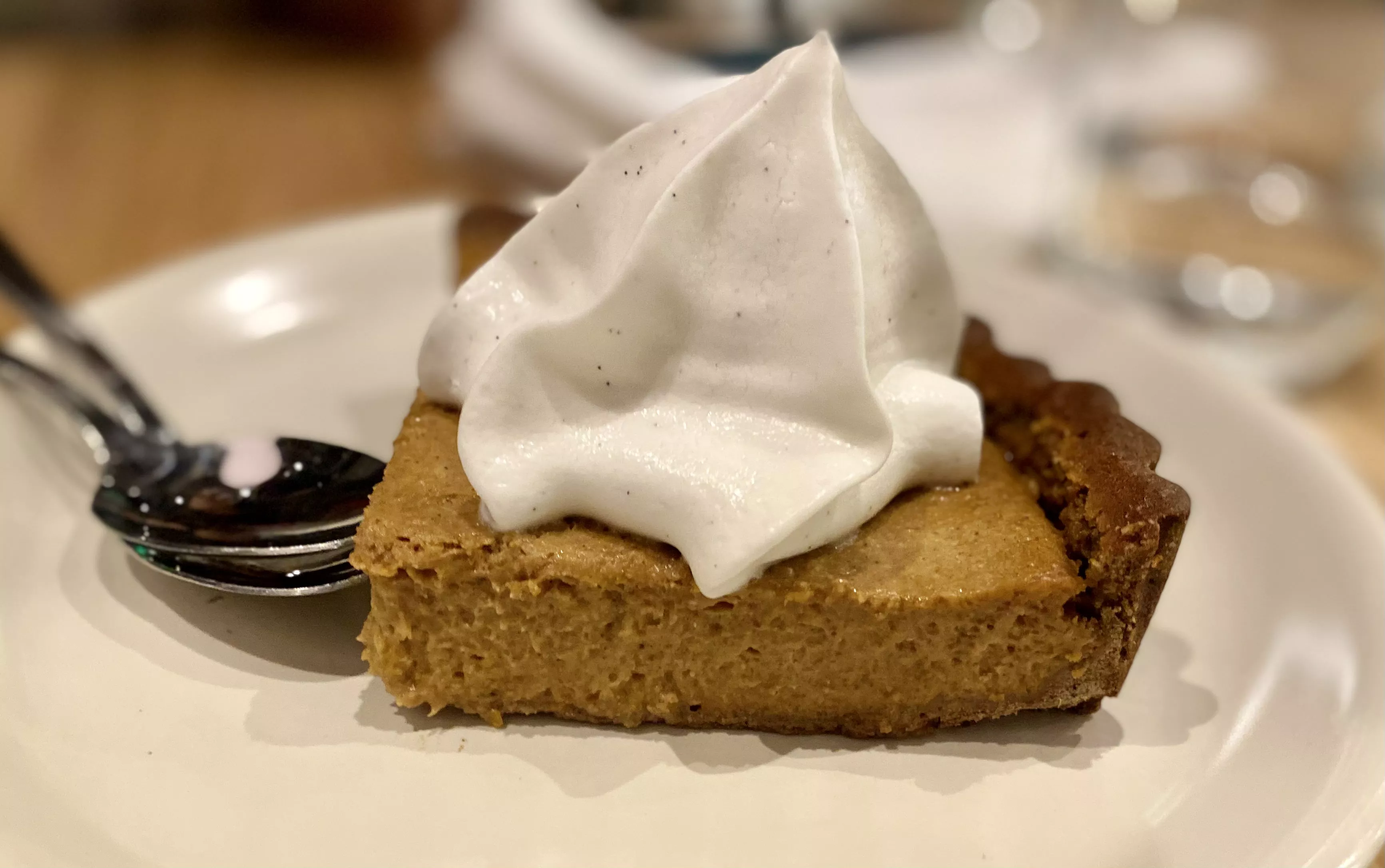 A slice of squash pie with coconut whipped cream