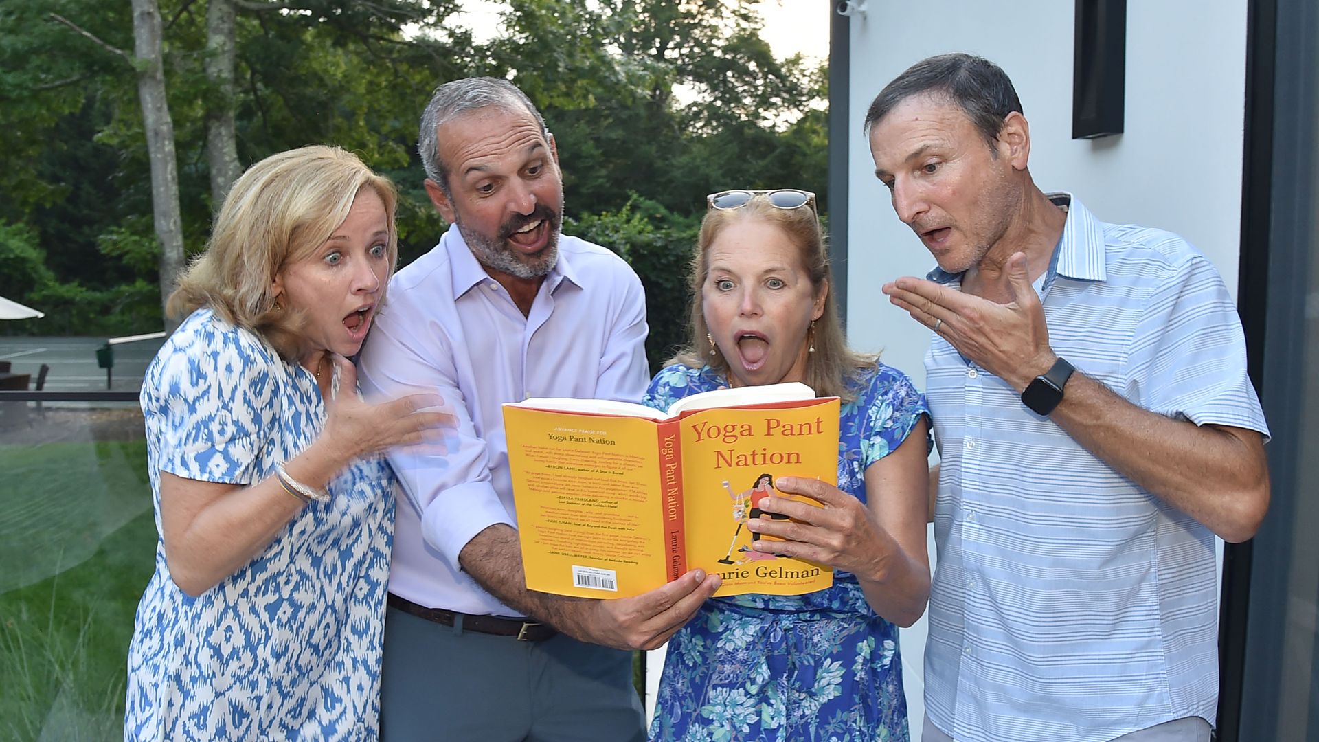Katie Couric holds a book with a shocked expression on her face.