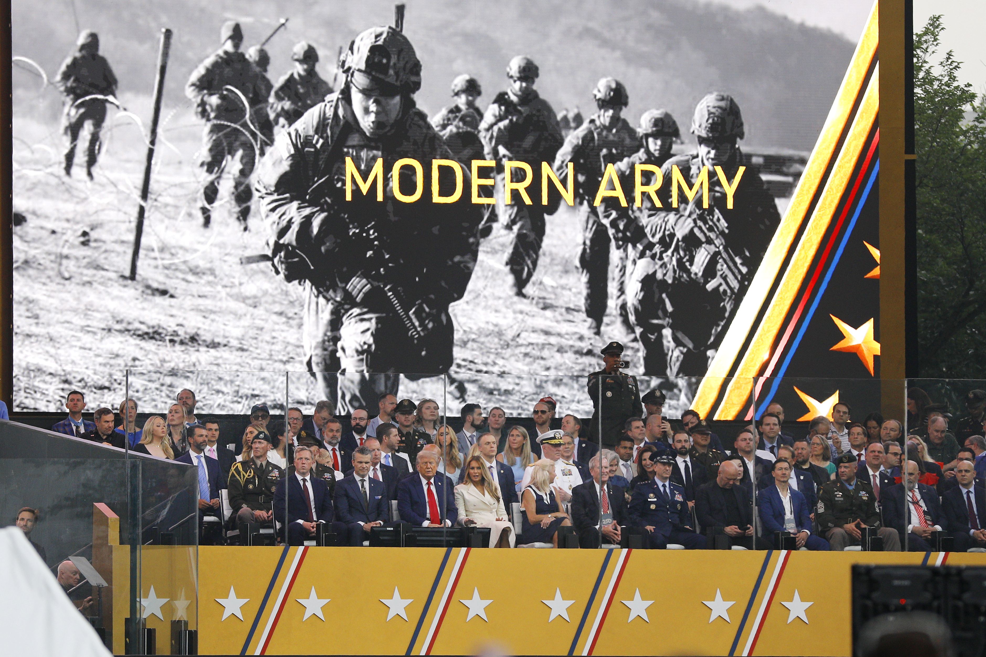 President Trump and guests sit on a stage