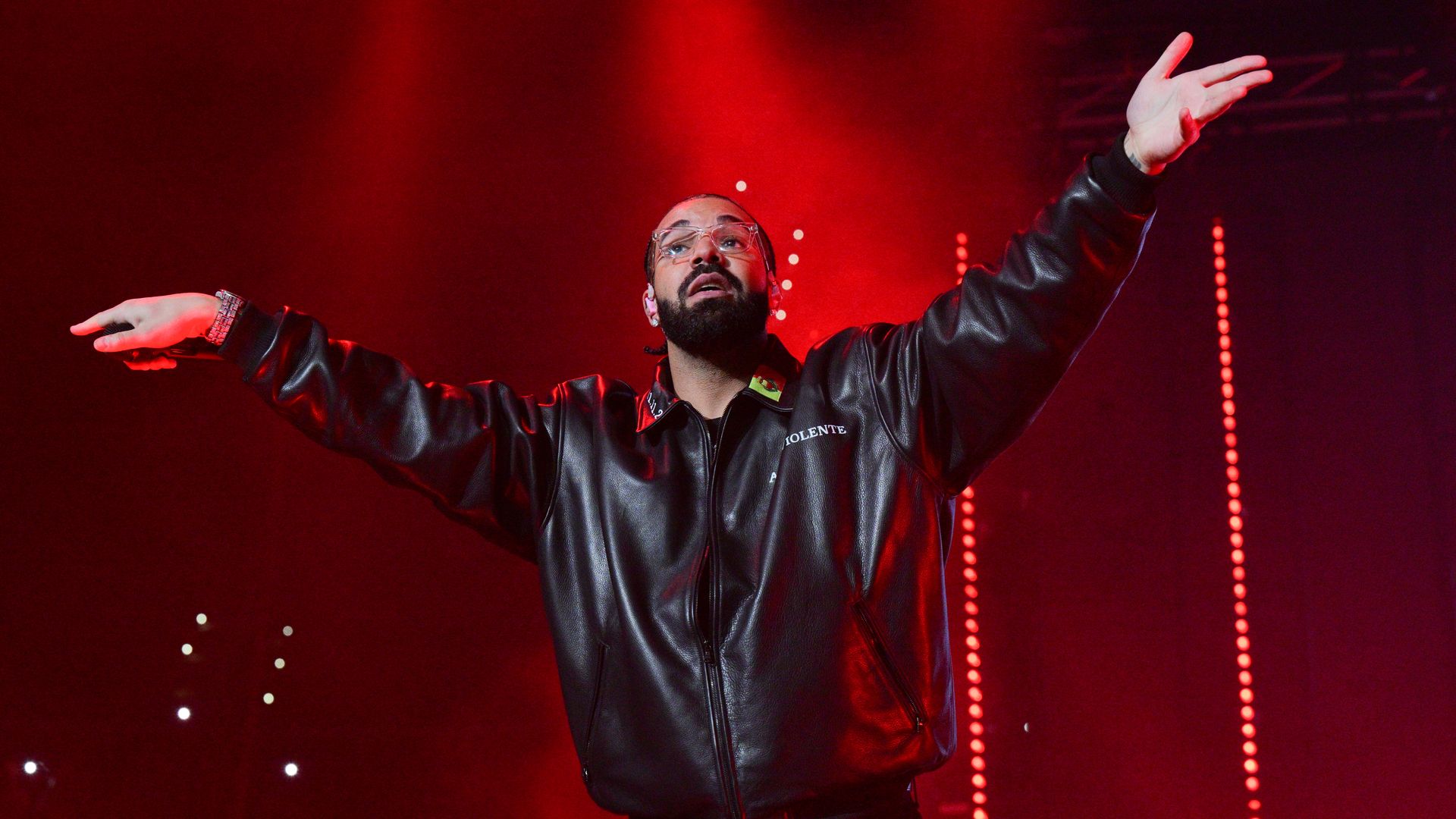 Drake performs on stage with his arms outstretched