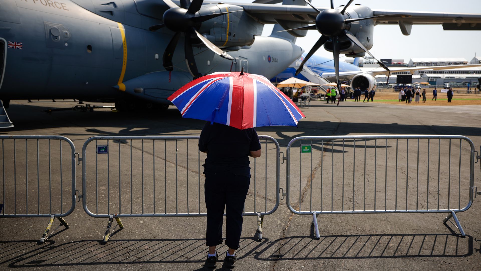  An attendee shelters from the sun under a Union Jack umbrella, during a heatwave, on the opening day of the Farnborough International Airshow in Farnborough, UK, on Monday, July 18, 2022.