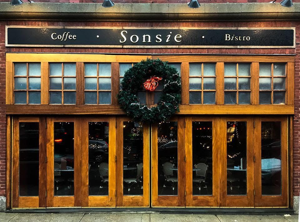 An exterior shot of Sonsie, the Back Bay Boston eatery, with a Christmas wreath and a red bow hanging outside.