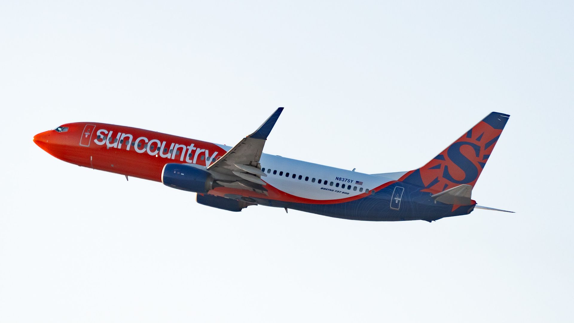 A Sun Country jet flies through the sky 