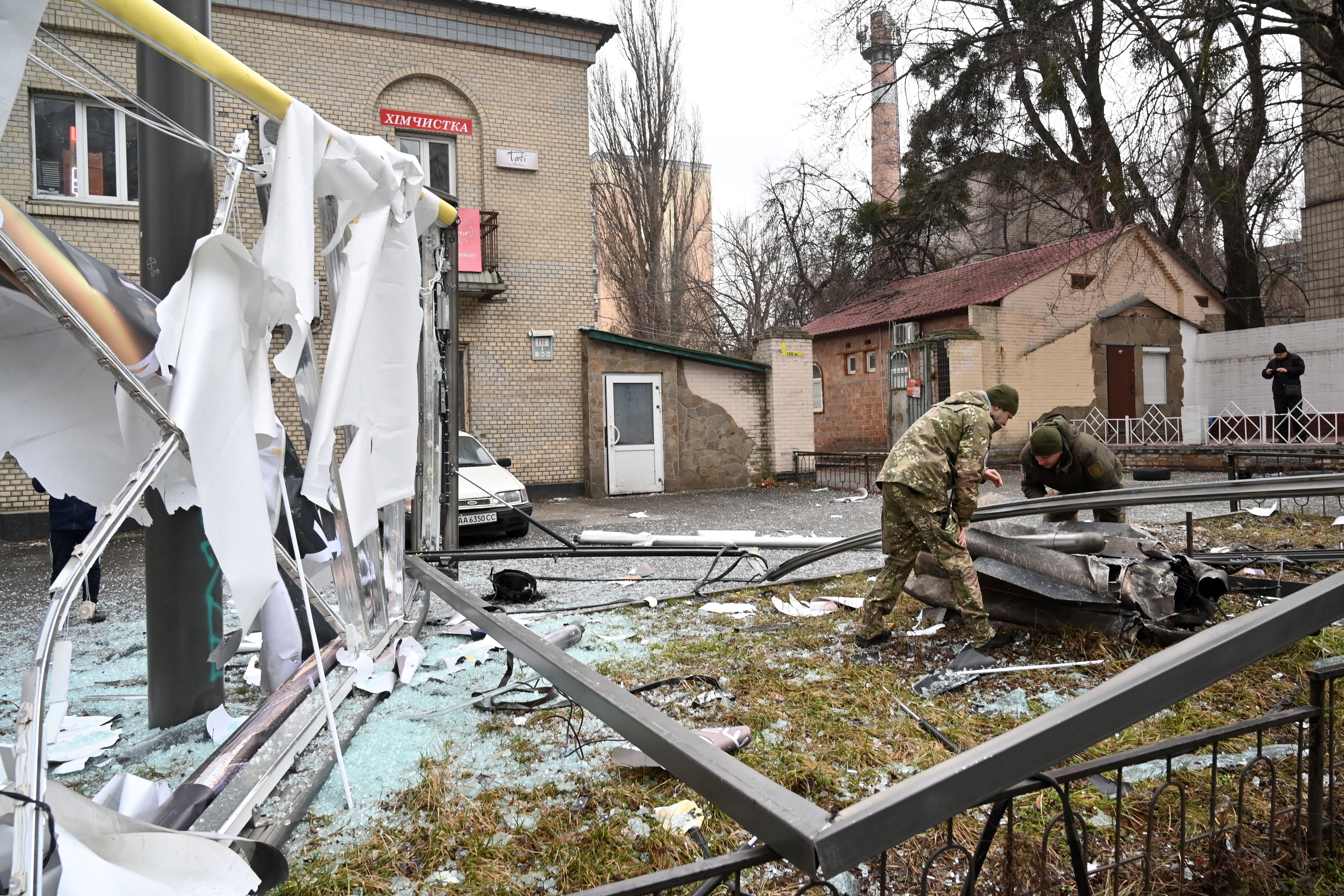Police and security personnel inspect the remains of a shell in a street in Kyiv on February 24
