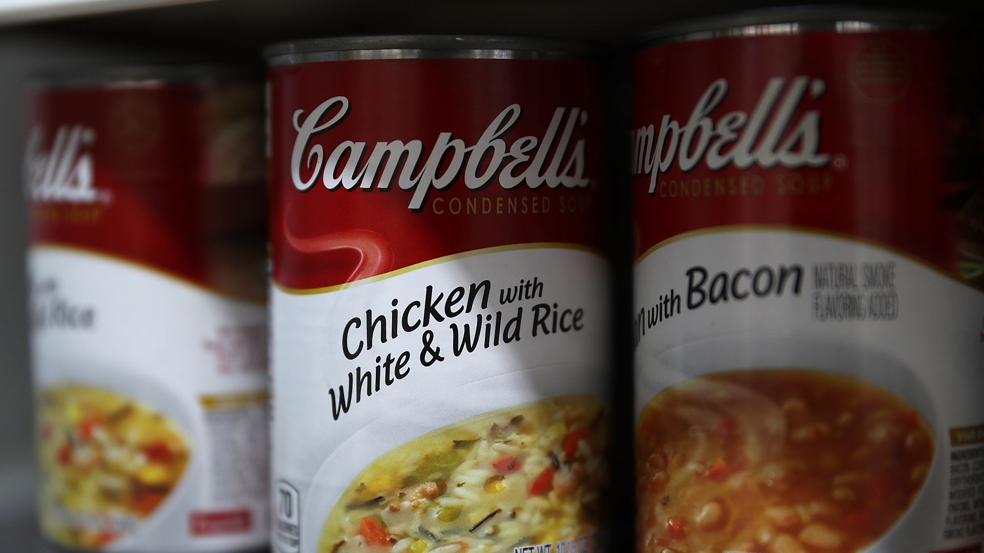 Cans of Campbell's soup are displayed on a supermarket shelf