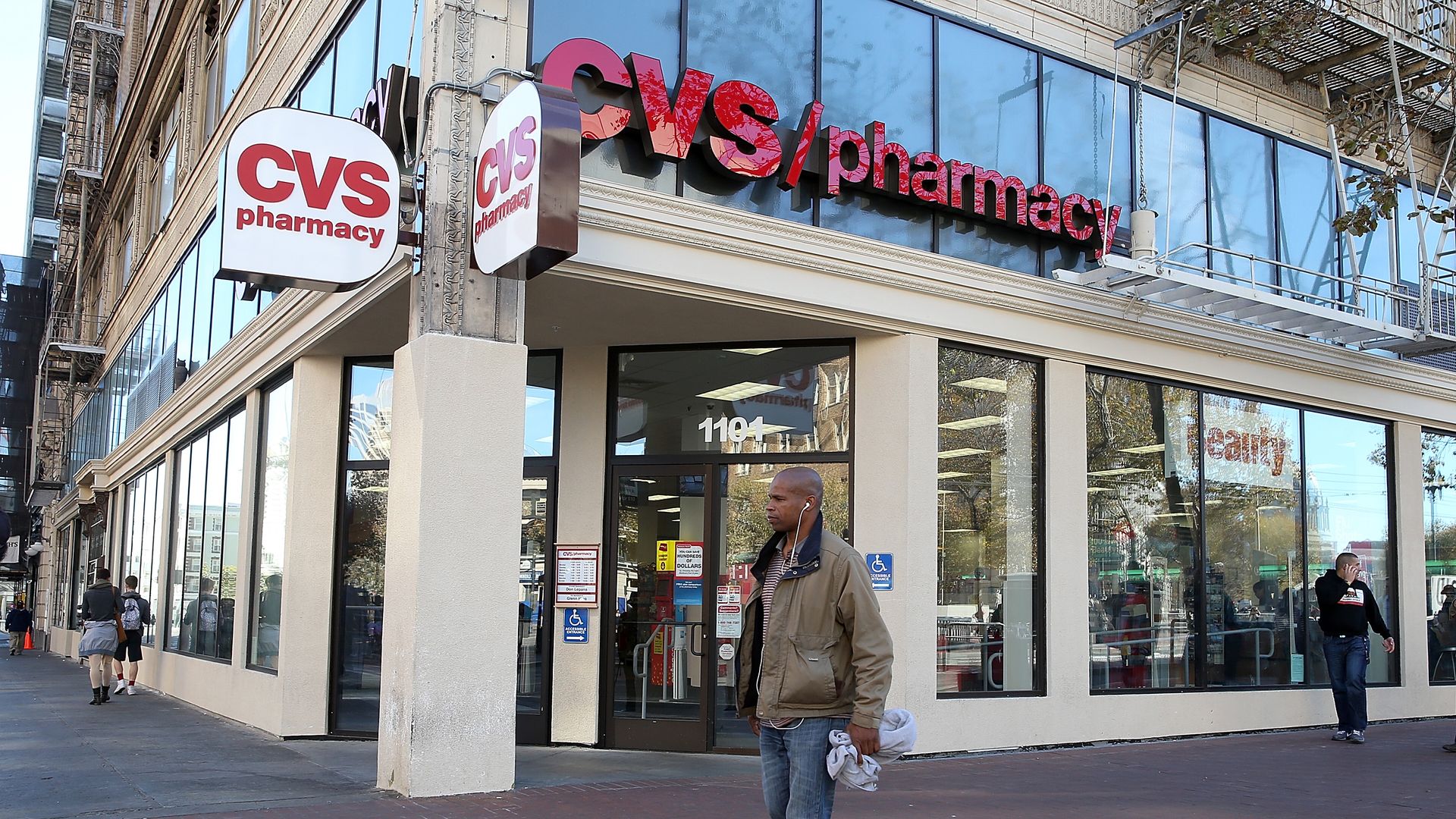 A man walks outside a CVS pharmacy building.