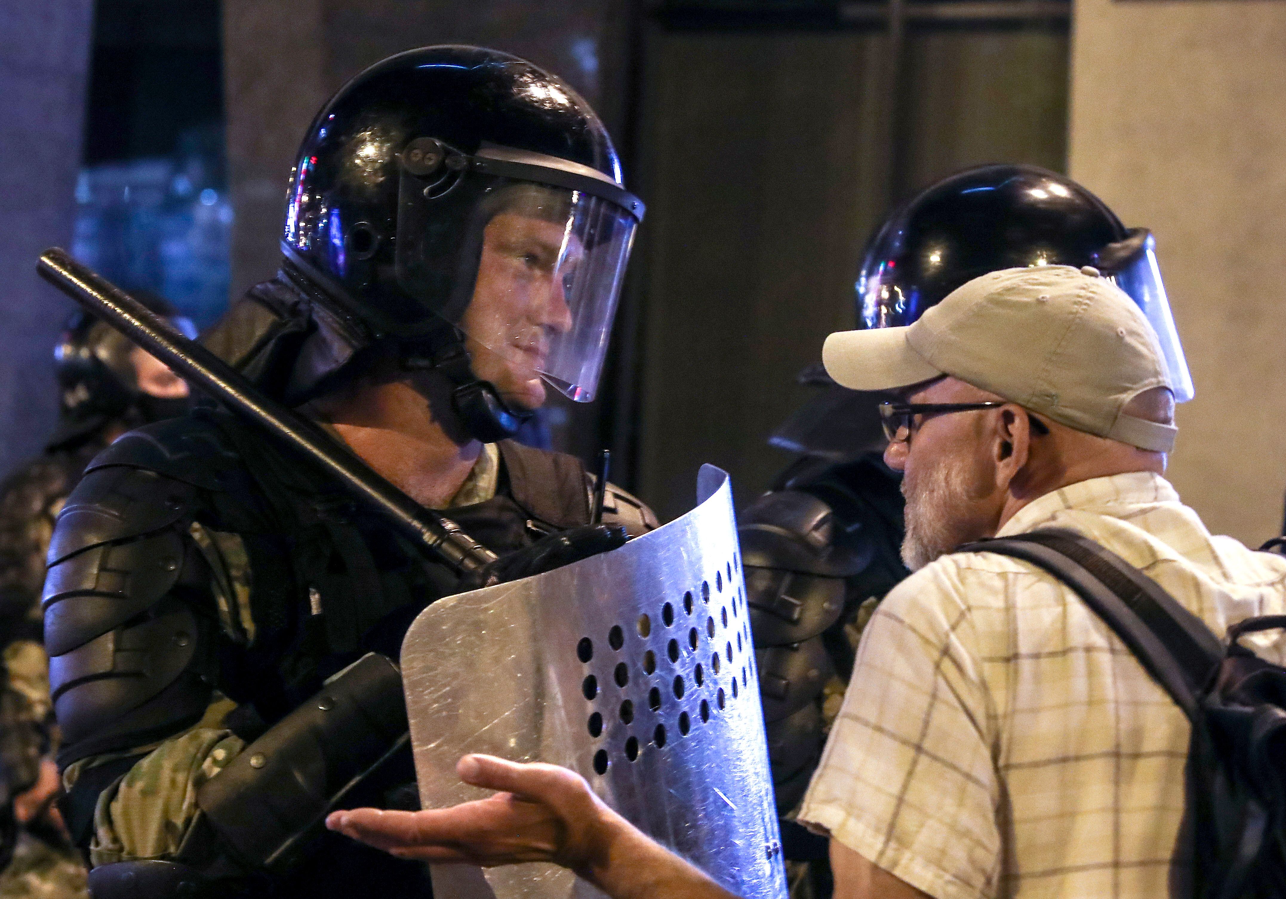 A man talks to a riot police officer during a protest against the results of the 2020 Belarusian presidential election. 