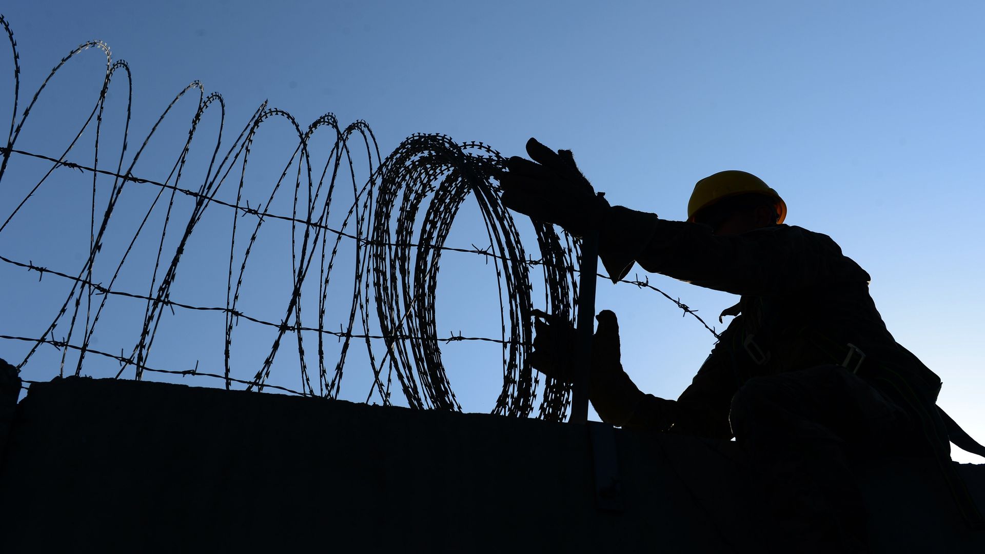 A US soldier removes barbed wire from a wall in Bagram Air Base
