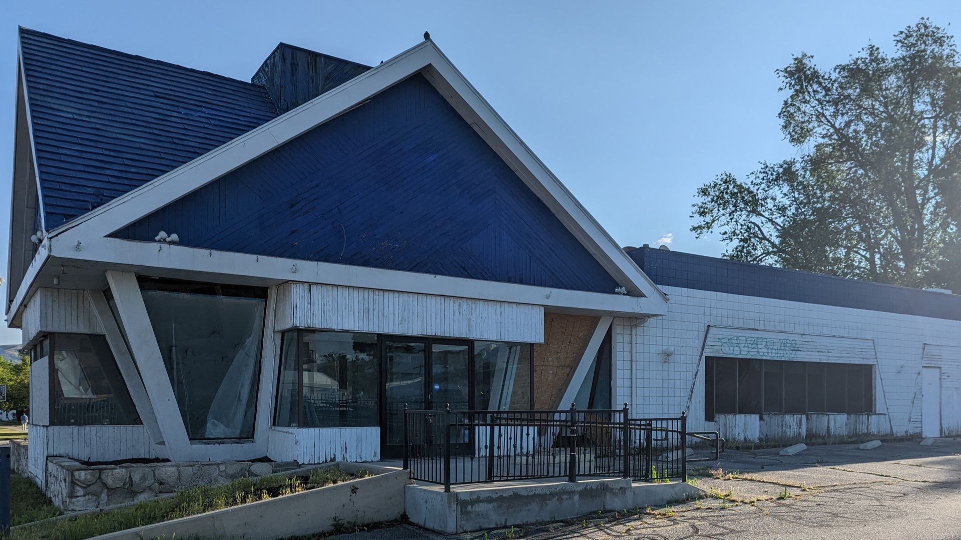A blue and white building has a pentagonal facade and trapezoidal windows.