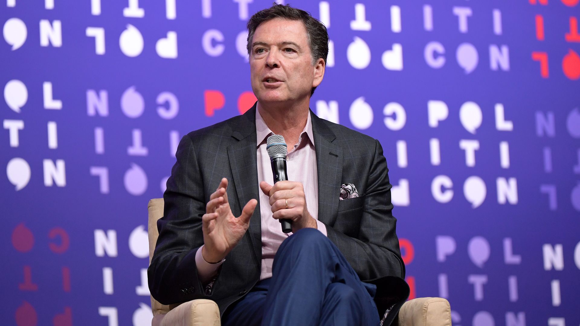 Former FBI Director James Comey sits in a chair and speaks into a mic as he is interviewed.