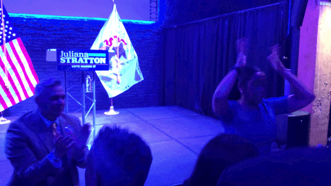 A woman dances at a party in front of a podium