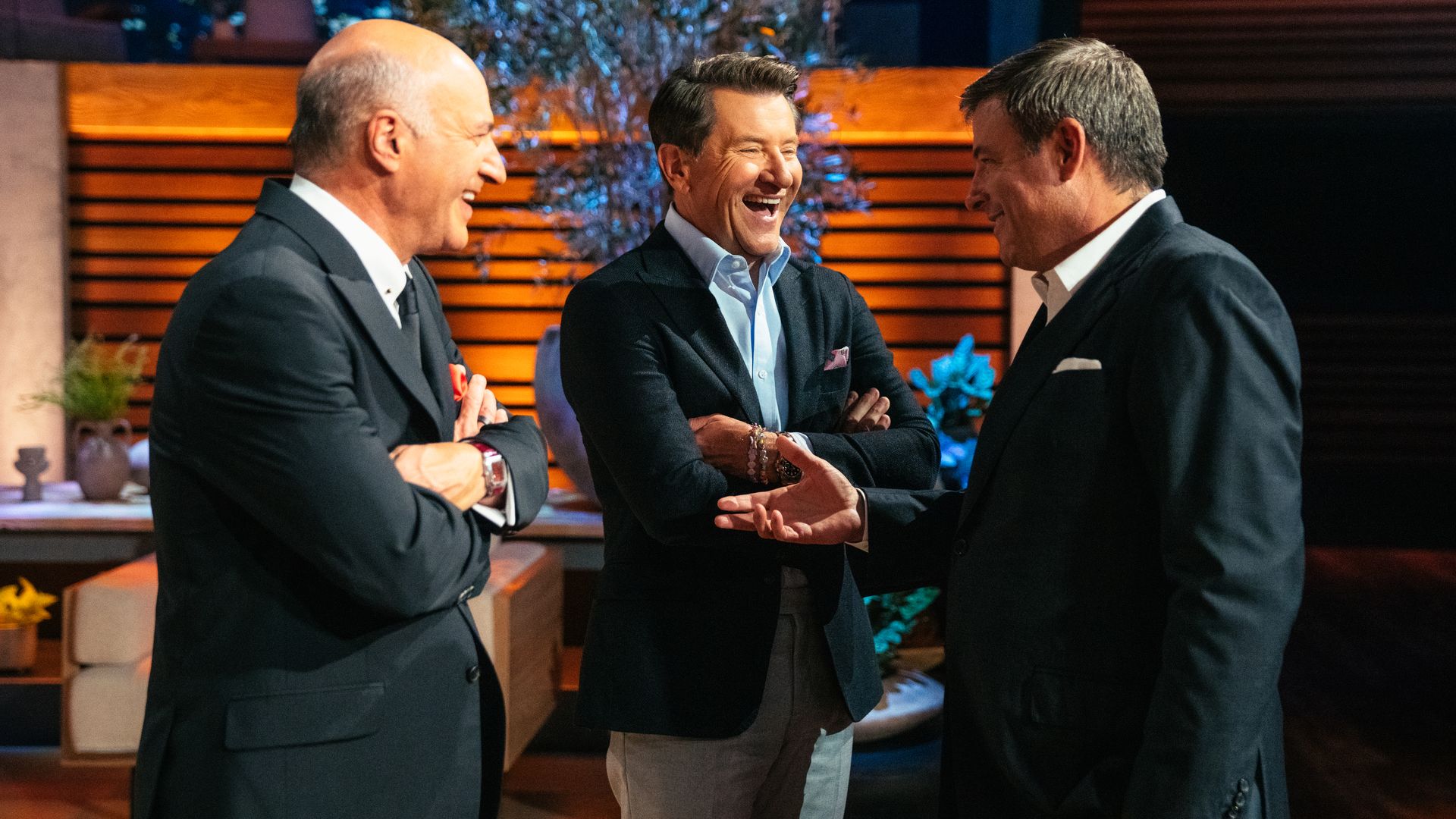 Three men are photographed as they have a lively conversation.
