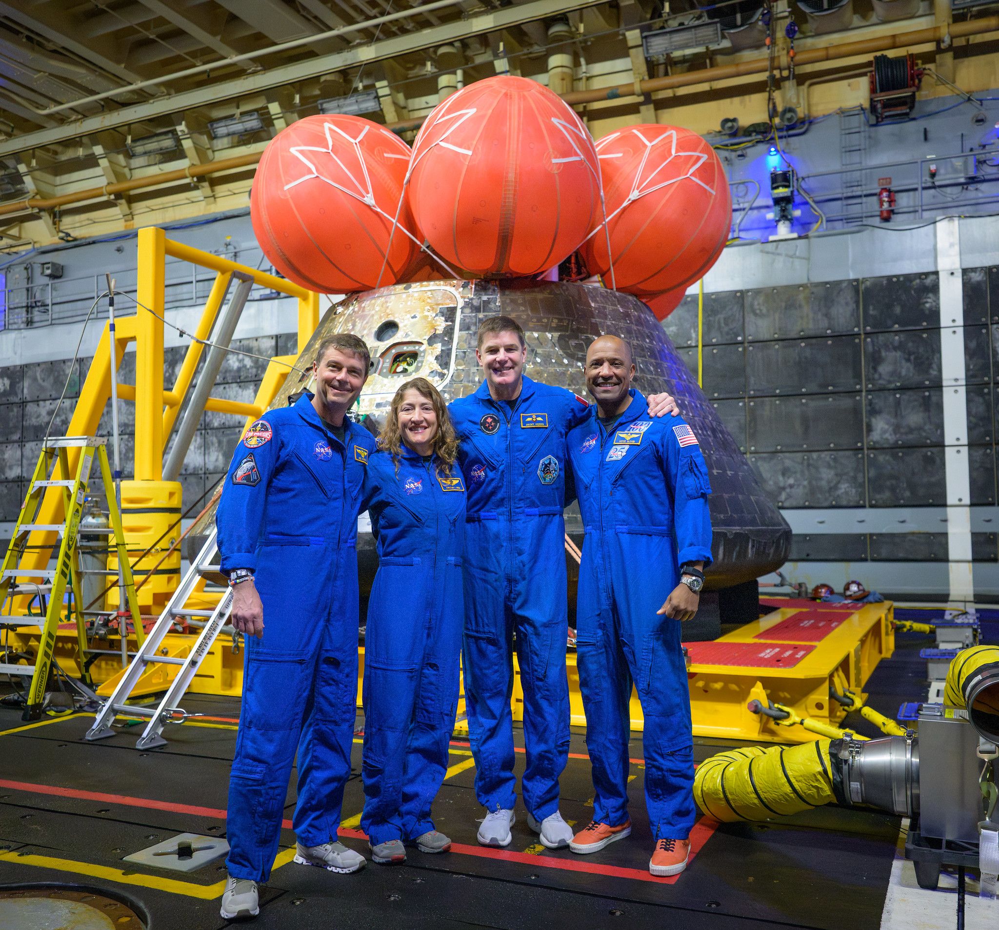 The Artemis II astronauts pose for a group photo after viewing their Orion spacecraft β which they named Integrity β in the well deck of USS John P. Murtha following their splashdown.