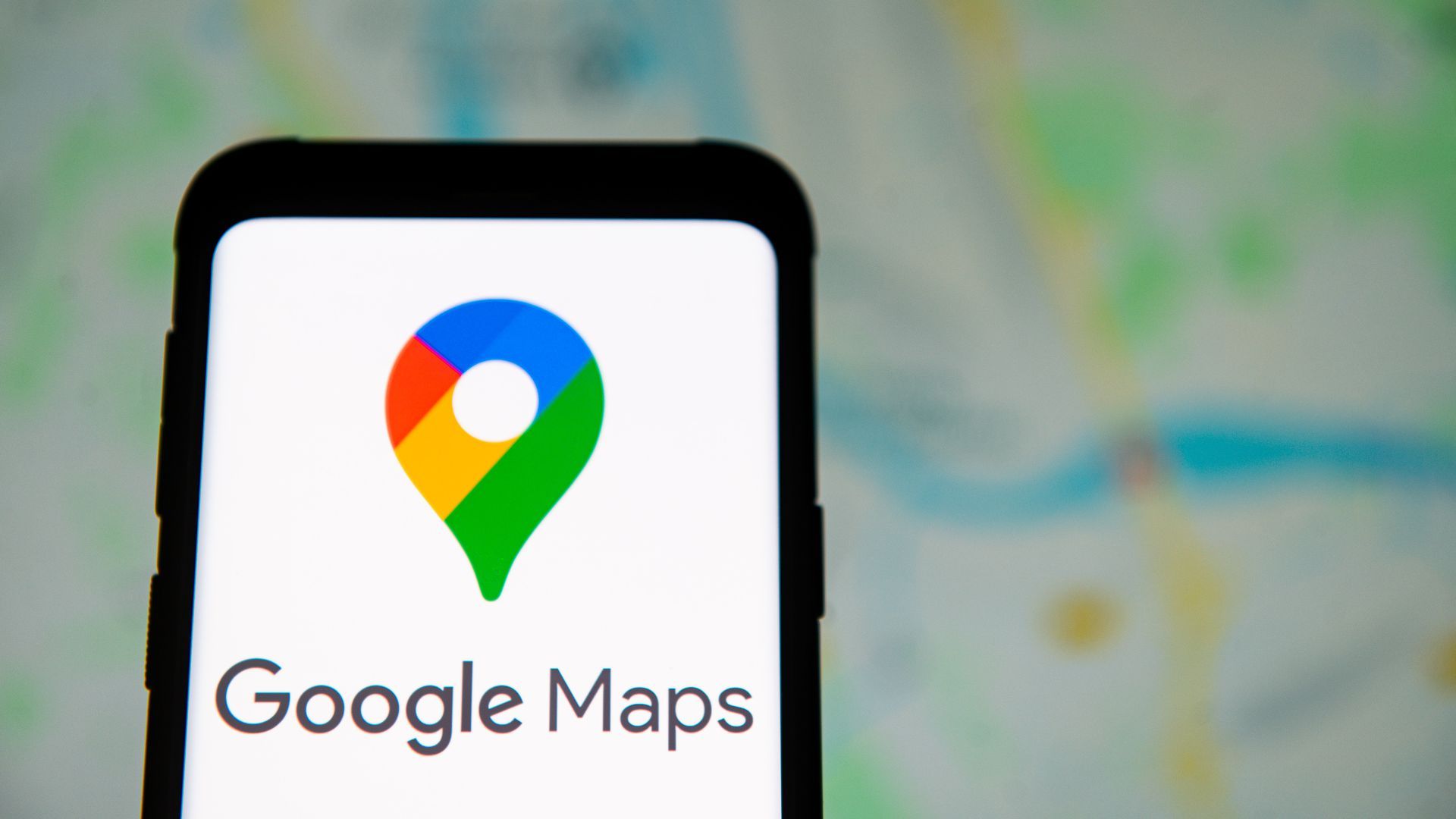 An illustration of the Google Maps logo on a smartphone with a blurred map in the background