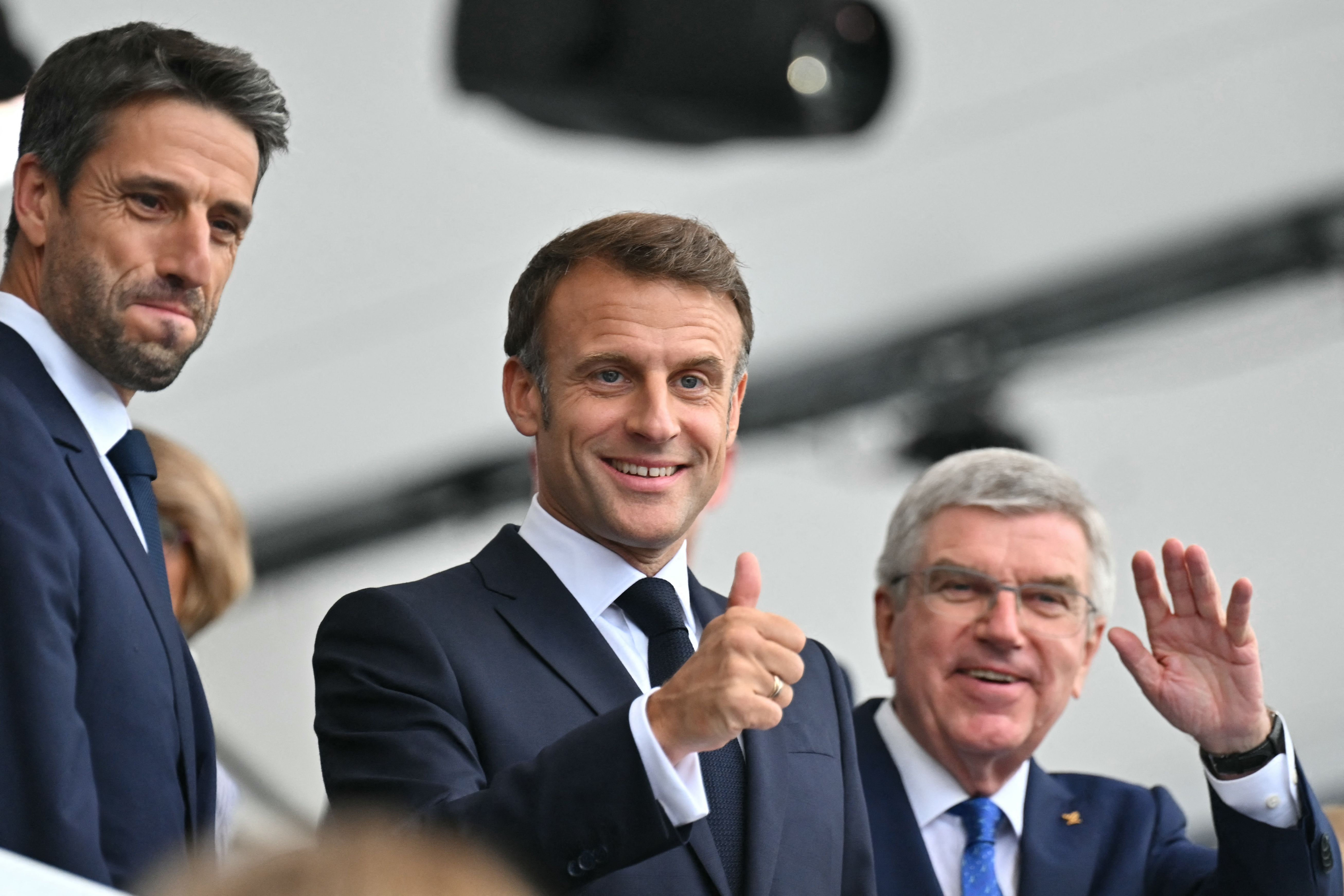 France's President Emmanuel Macron (C), President of the Organizing Committee for the Paris 2024 Olympic and Paralympic Games (Cojop) Tony Estanguet (L) and President of the International Olympic Committee (IOC) Thomas Bach (R) wave as they arrive to attend the opening ceremony of the Paris 2024 Oly