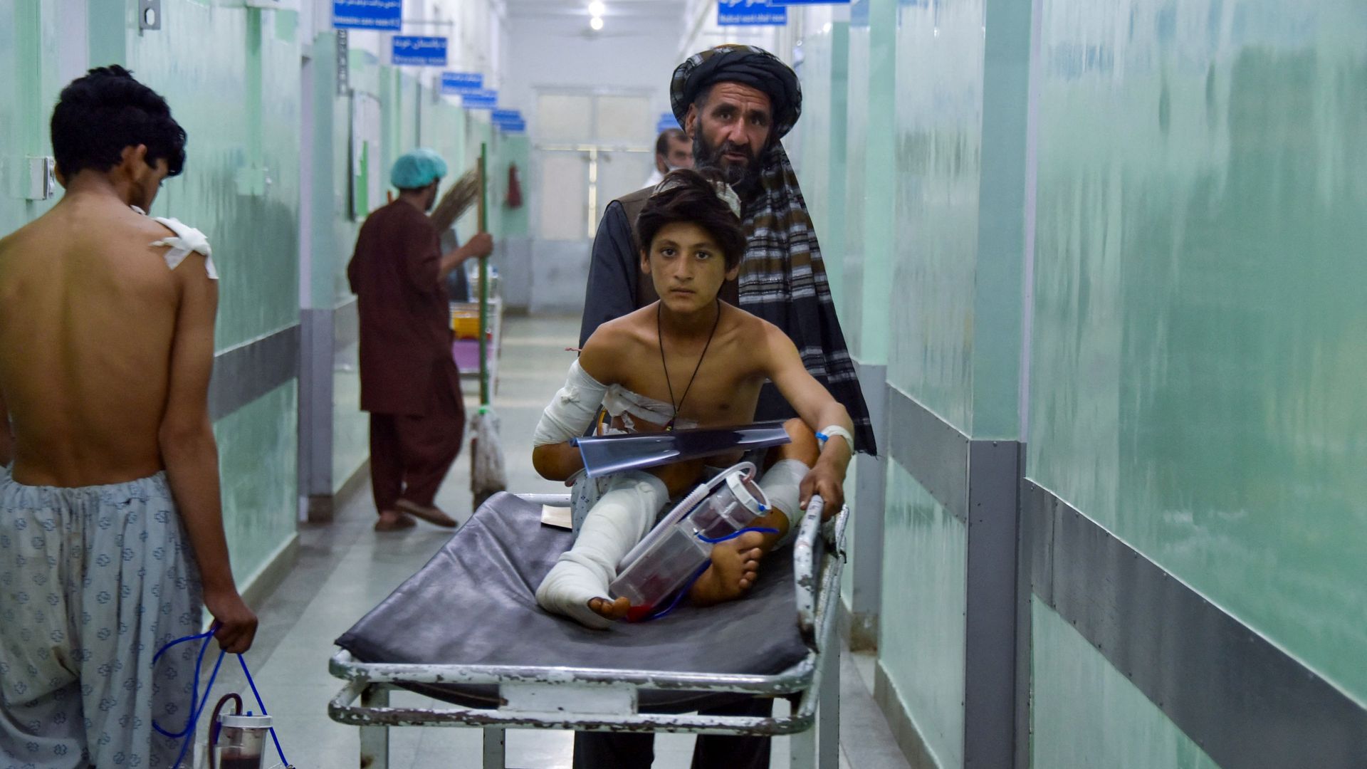 A man pushes an injured boy on a stretcher along a hospital corridor in Kandahar on May 10