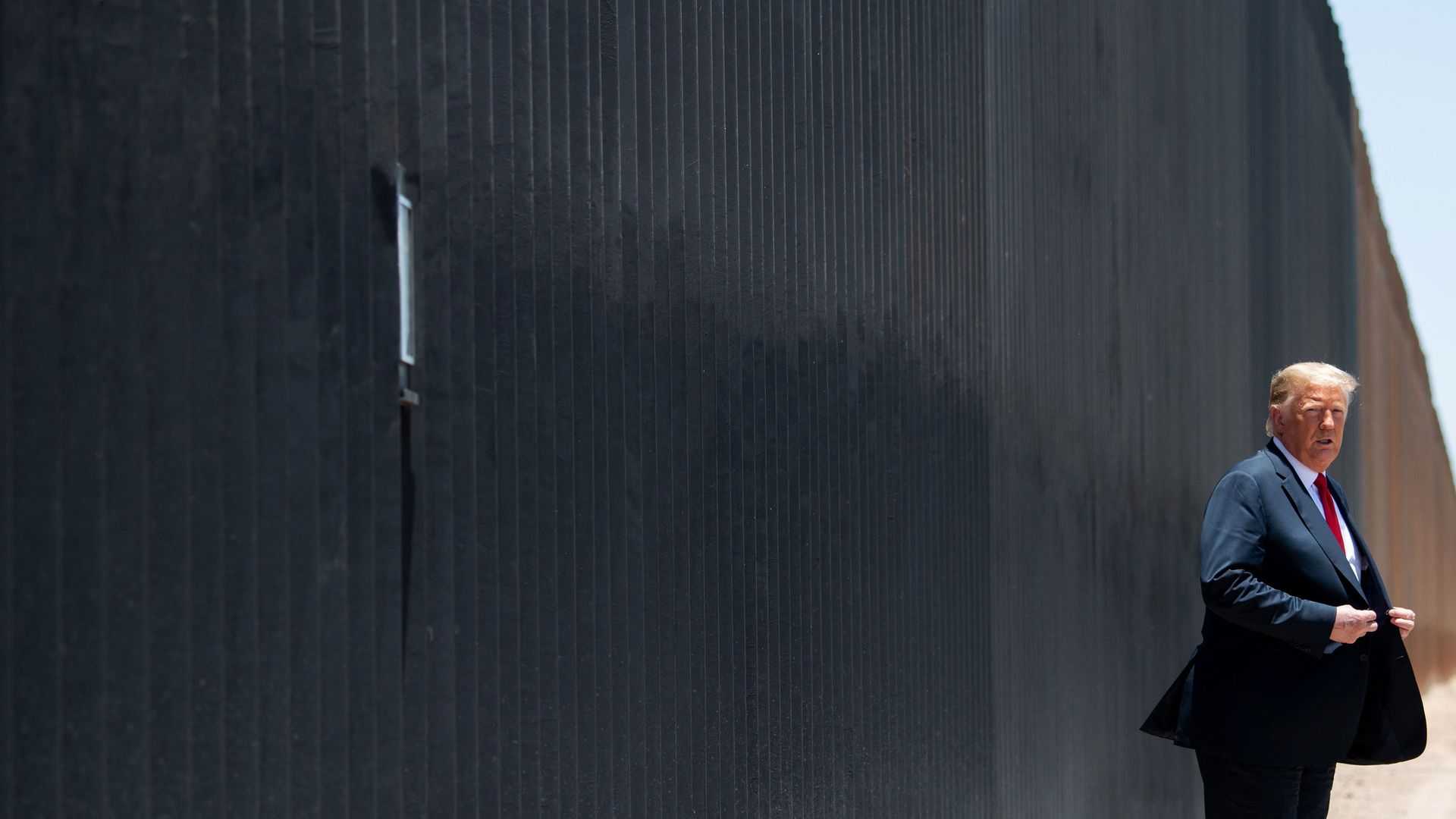 President Trump stands in front of a border wall