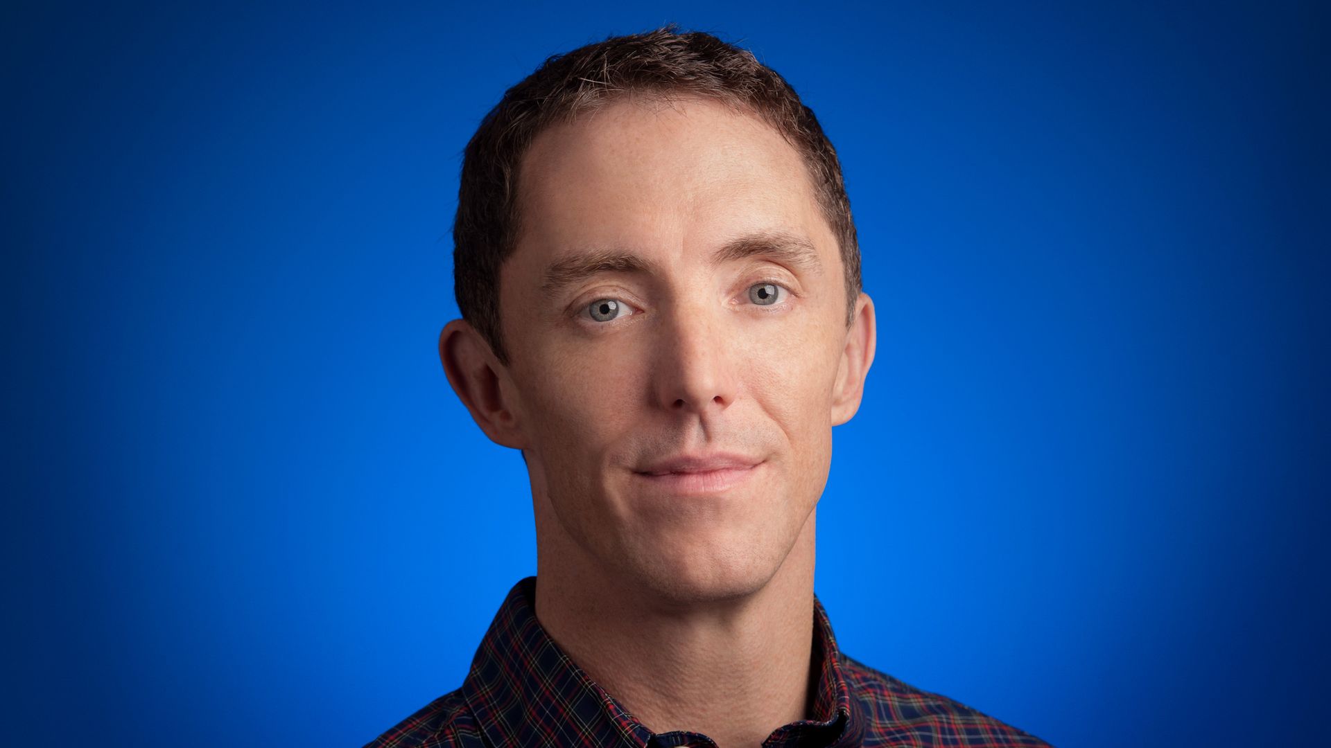 Keith Enright sits against a blue backdrop