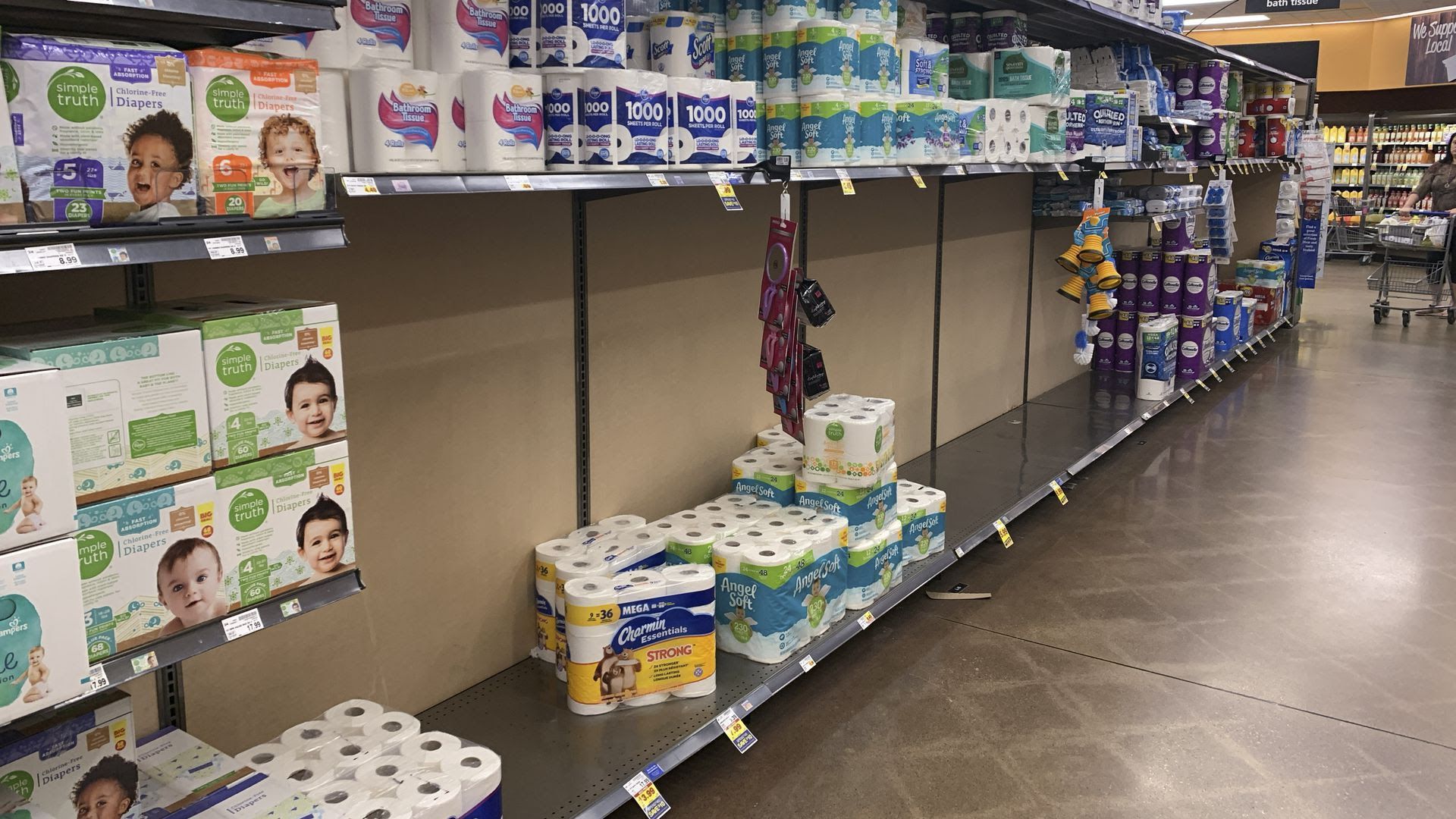 A grocery store aisle sporadically filled with toilet paper