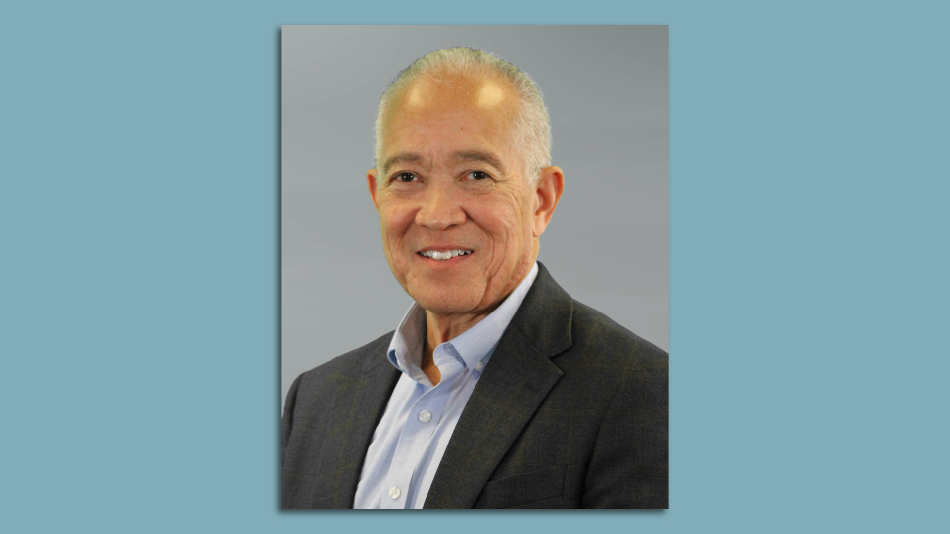 Photo of a man wearing a suit with a blue shirt.