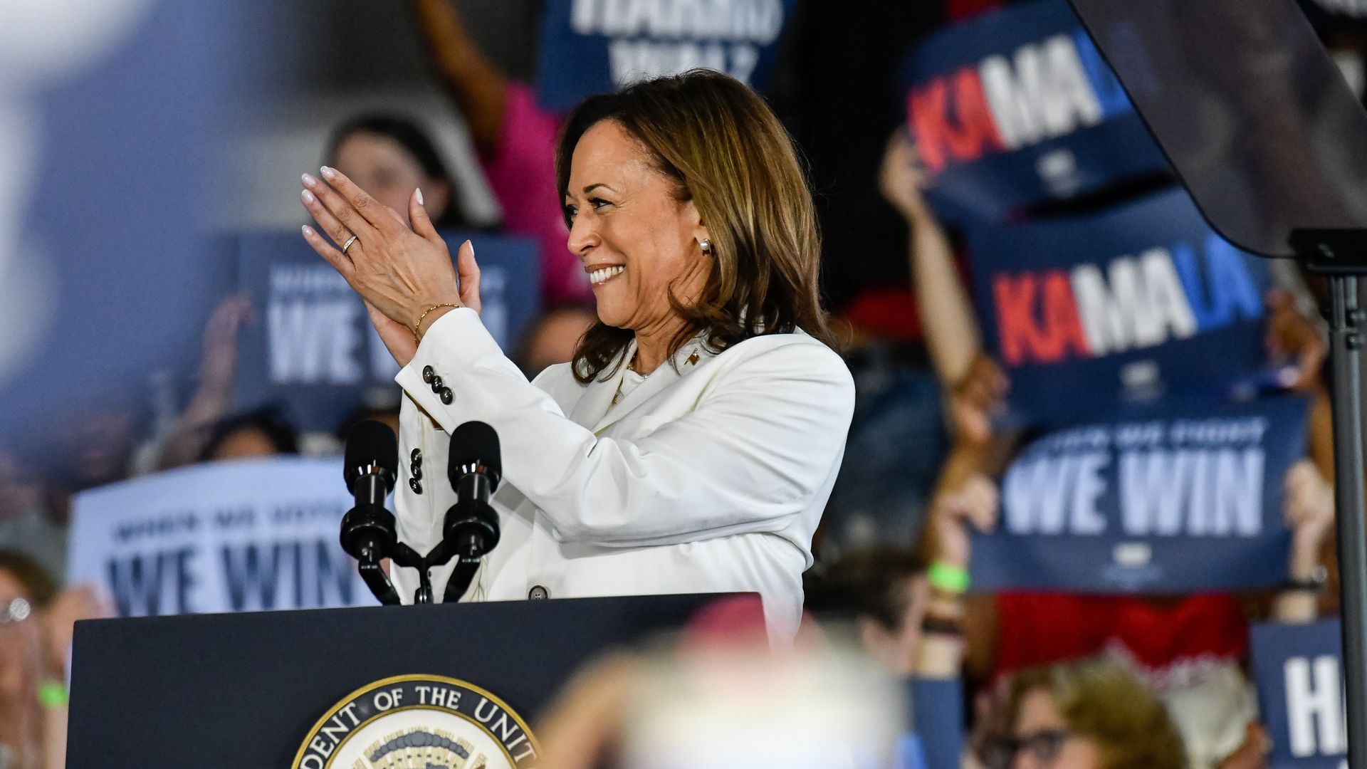 Kamala Harris claps before a crowd on a campaign stop.