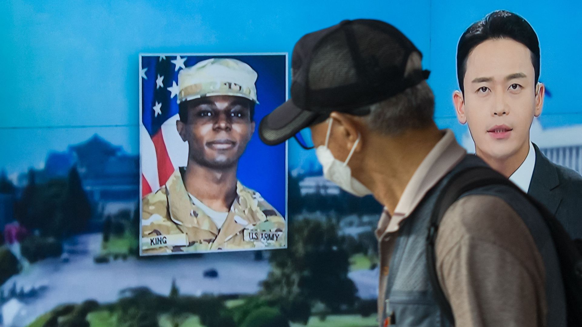 man walks past a television showing a news broadcast featuring a photo of US soldier Travis King