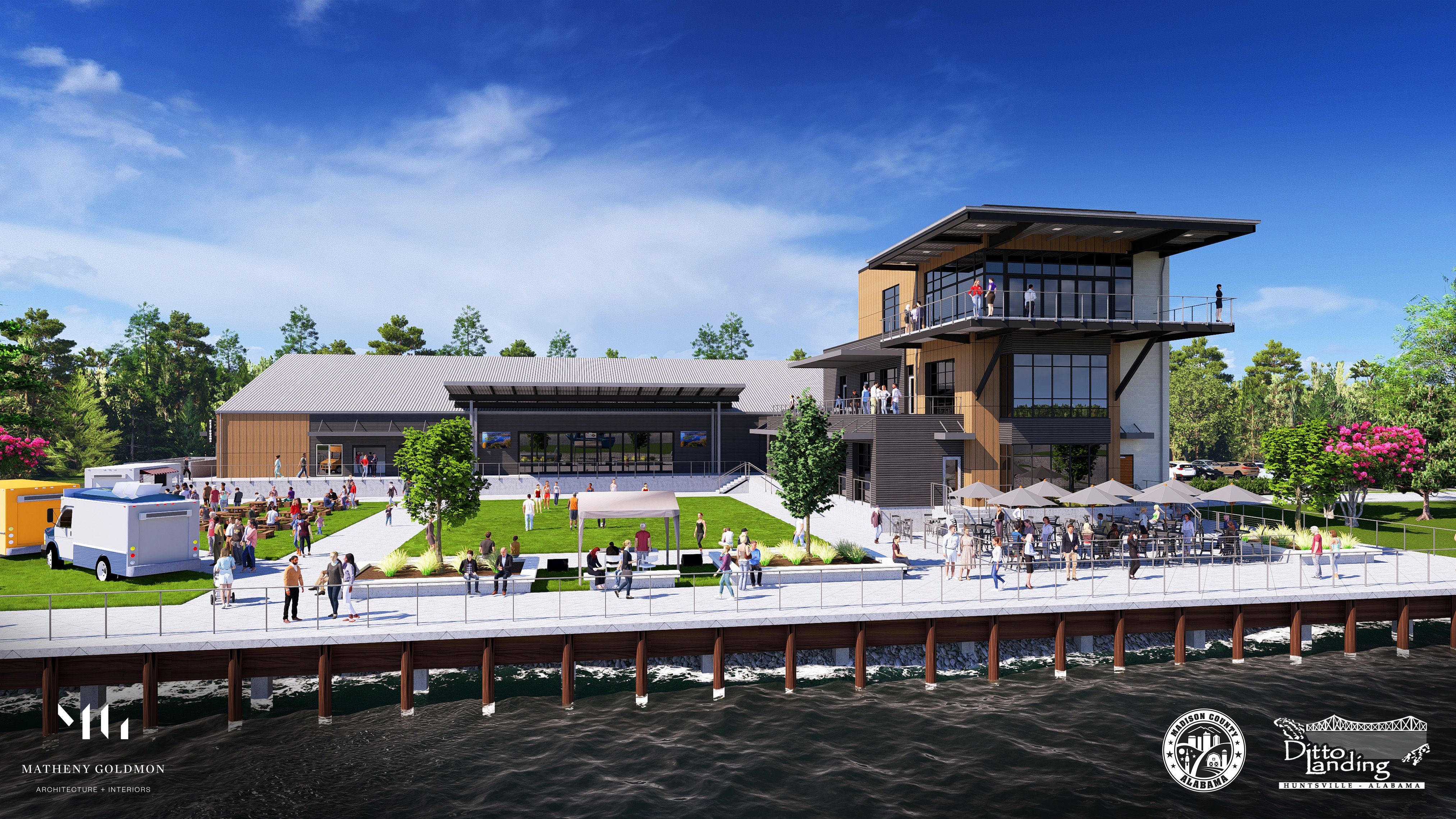 Waterfront building with outdoor dining and balconies, surrounded by green lawn and people enjoying sunny day by the water. Food trucks and trees in the background.