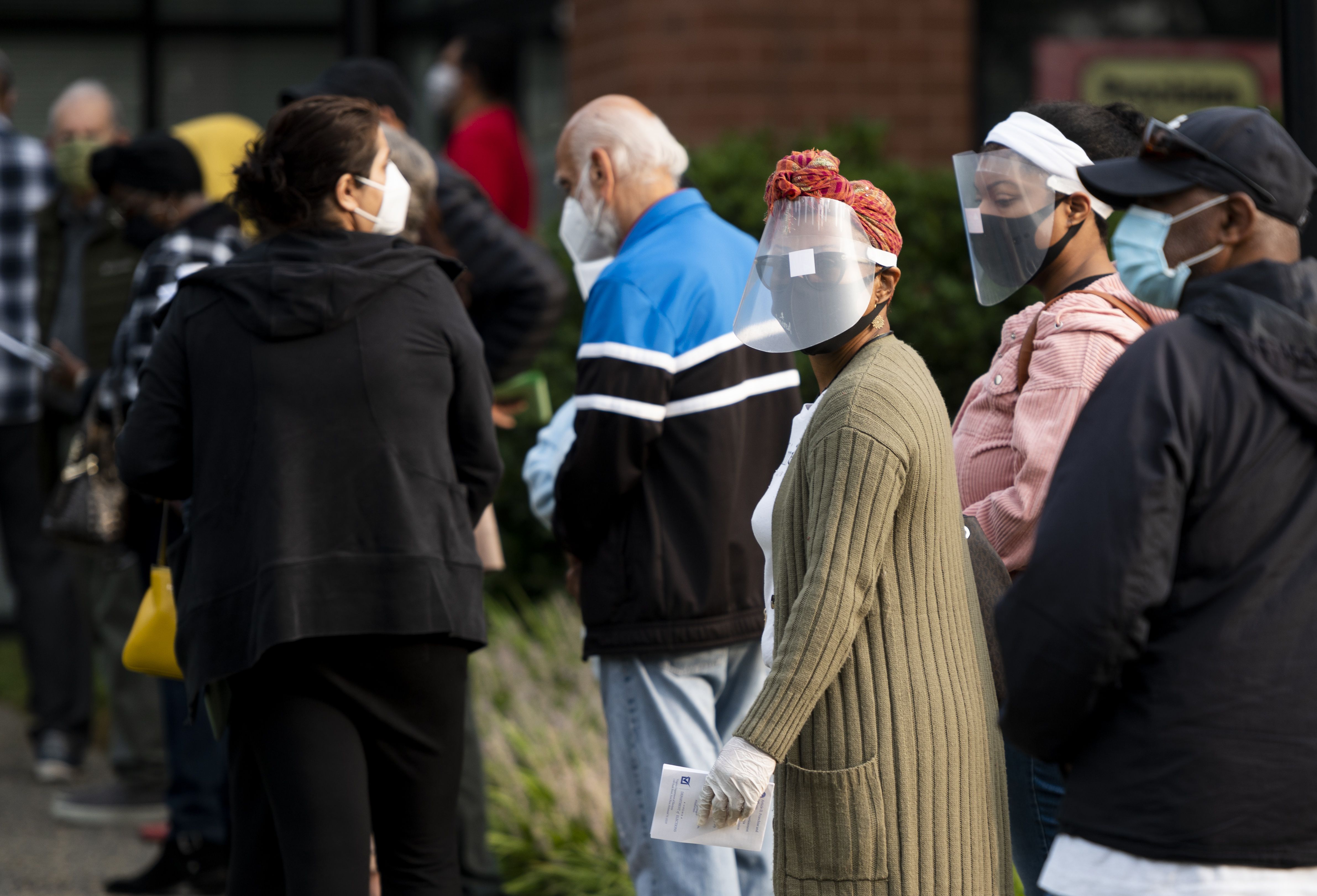 Voters wearing face masks wait in line for the Loudoun County 