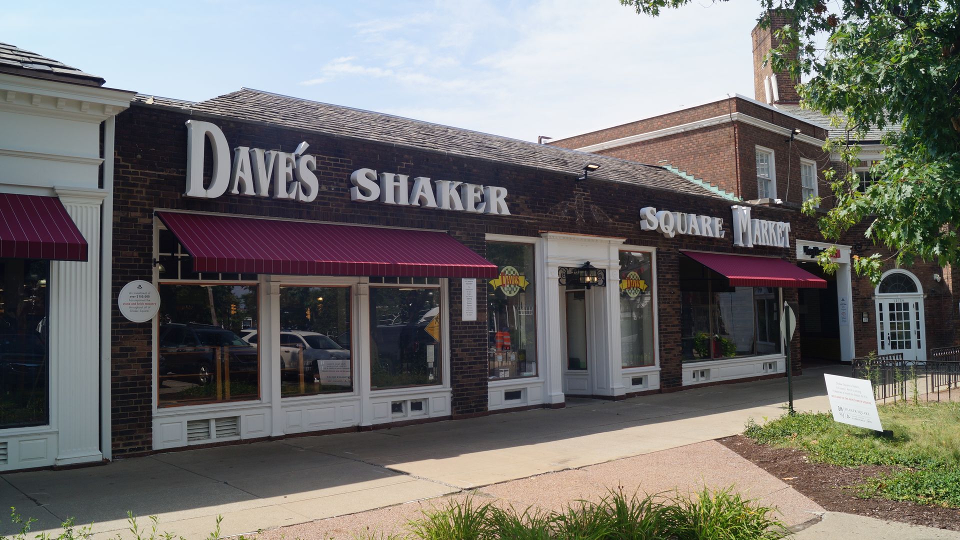 Exterior photo of Dave's Market in an urban shopping plaza, red awning