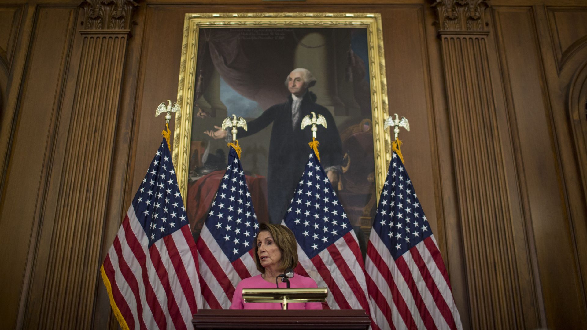 Nancy Pelosi standing in front of a portrait of George Washington